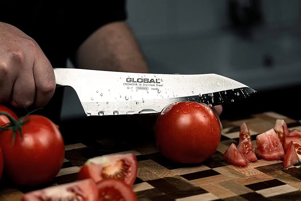 A deba knife slicing a tomato.