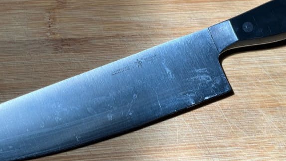 The Henckels Statement 8-inch Chef's Knife on a cutting board. 