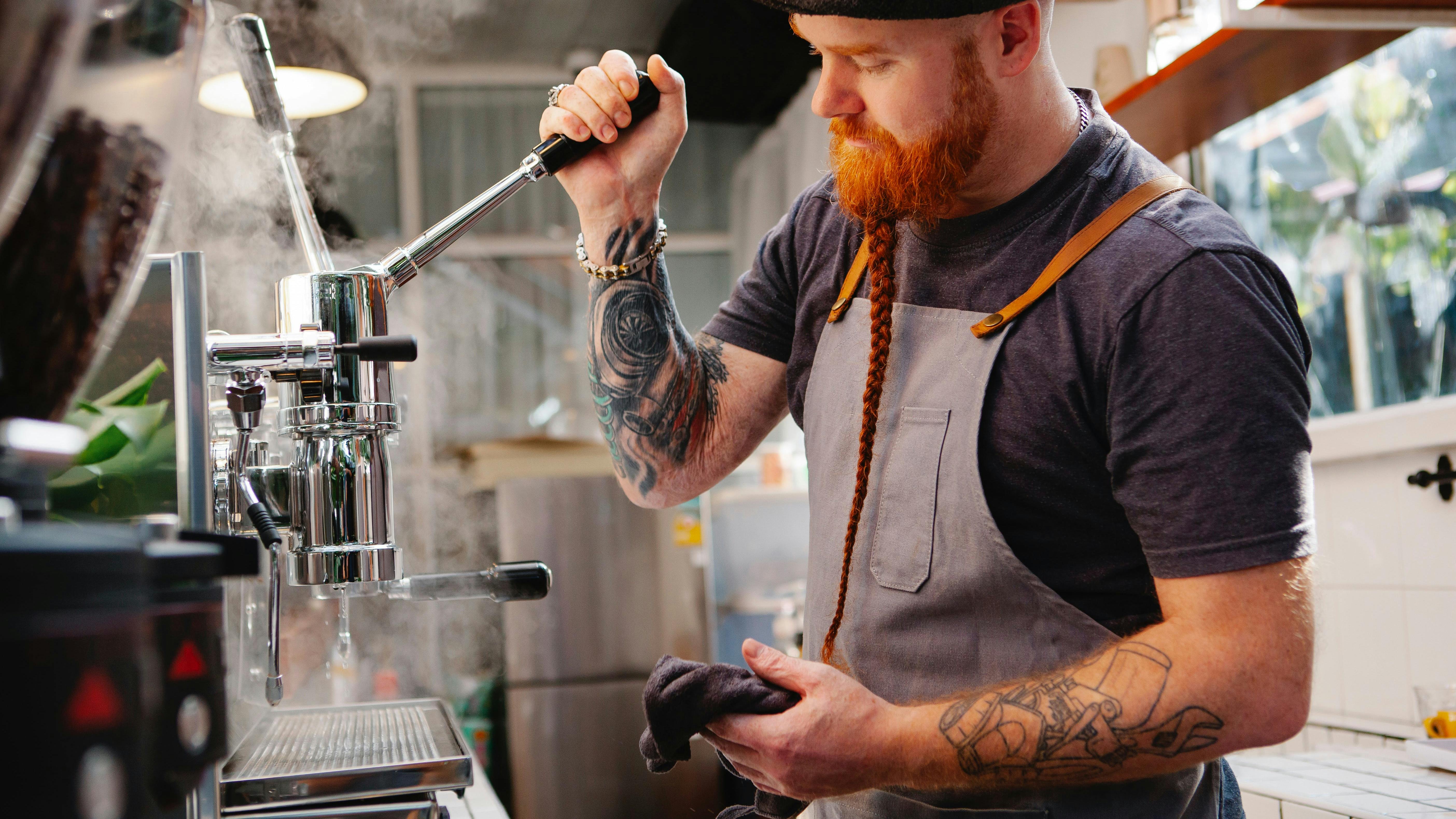 Barista using a high-end manual espresso machine to pull a shot in a cafe.