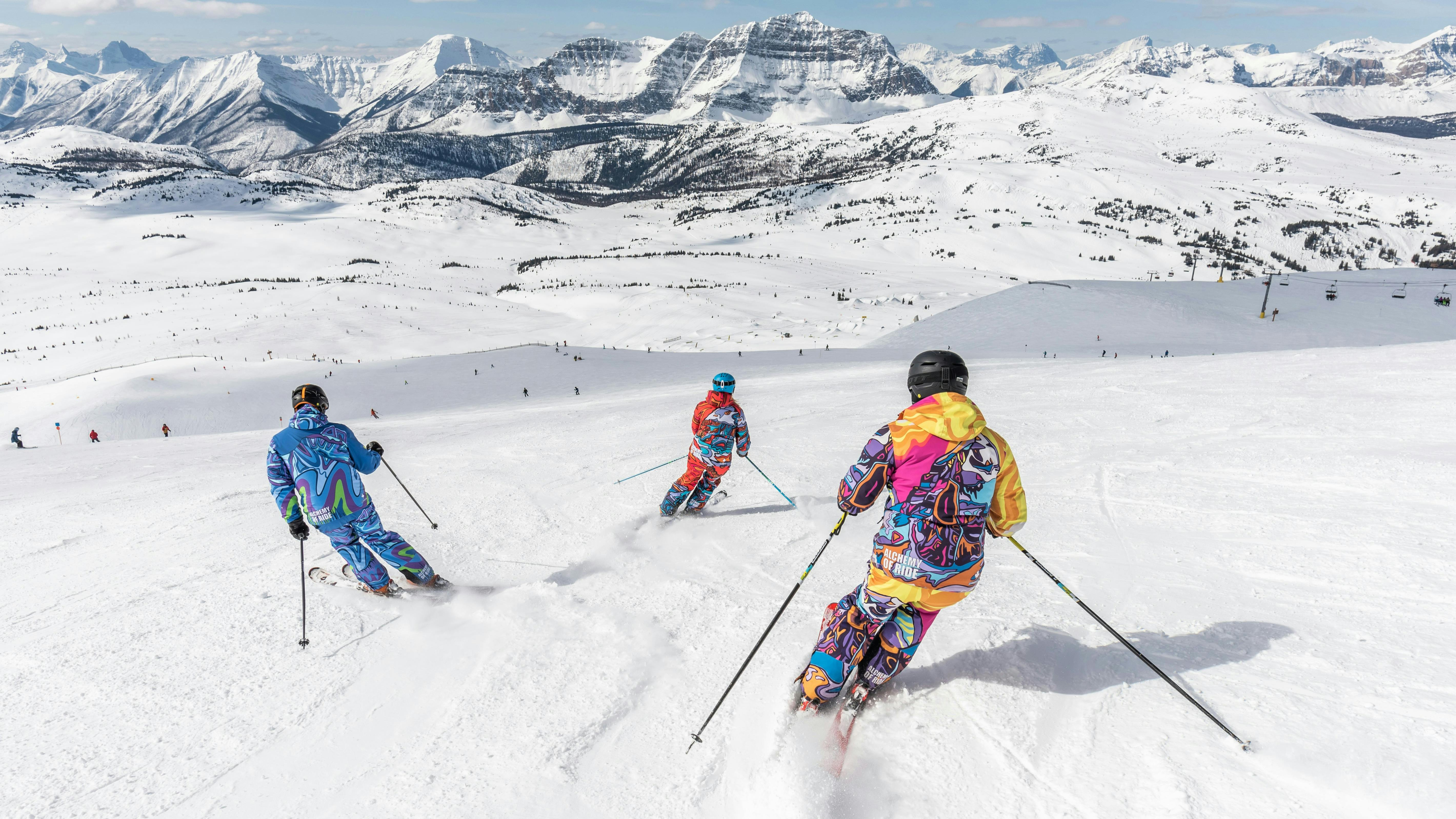 Three skiers turning down a snowy mountain. 