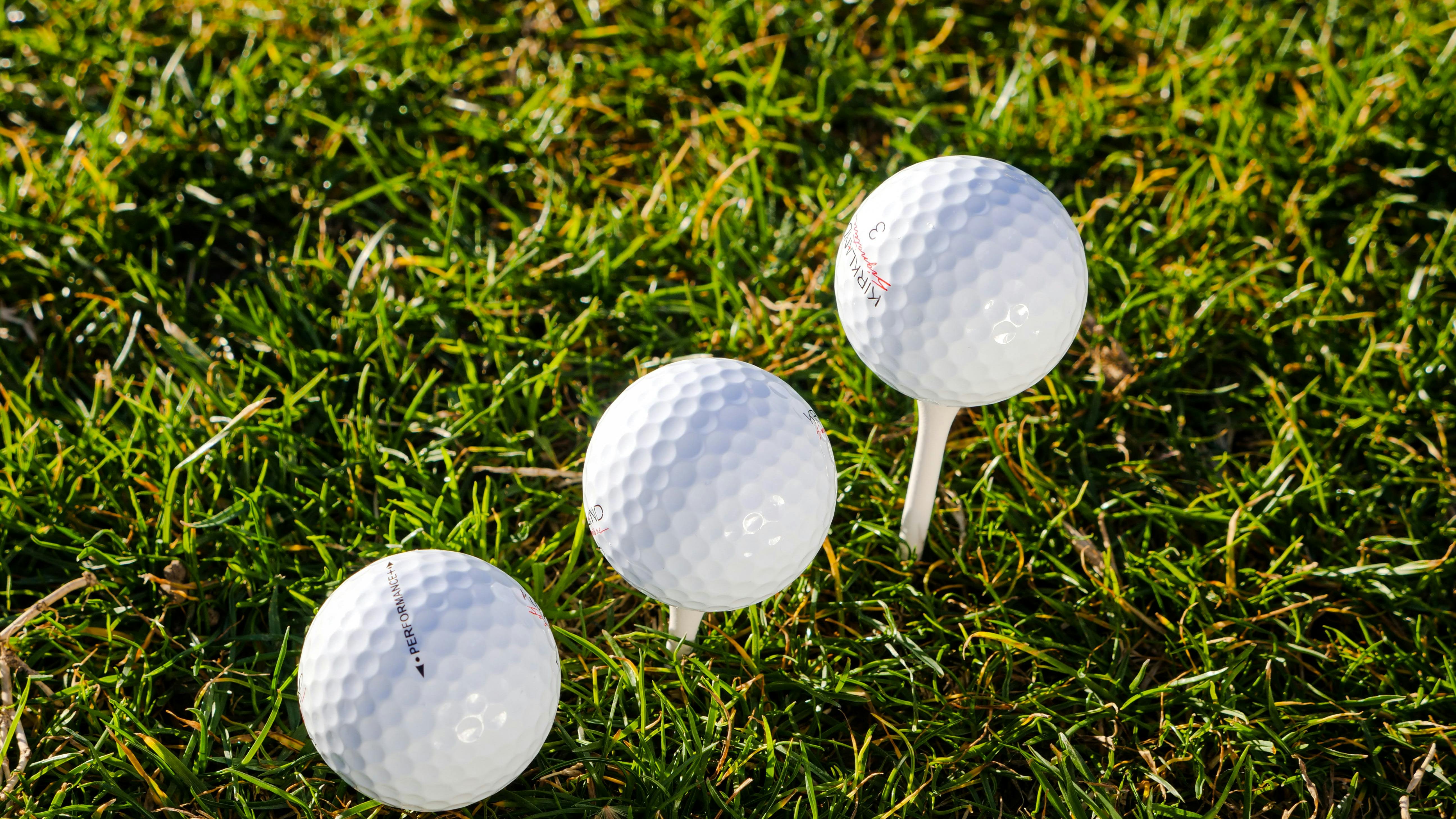Three golf balls on tees.