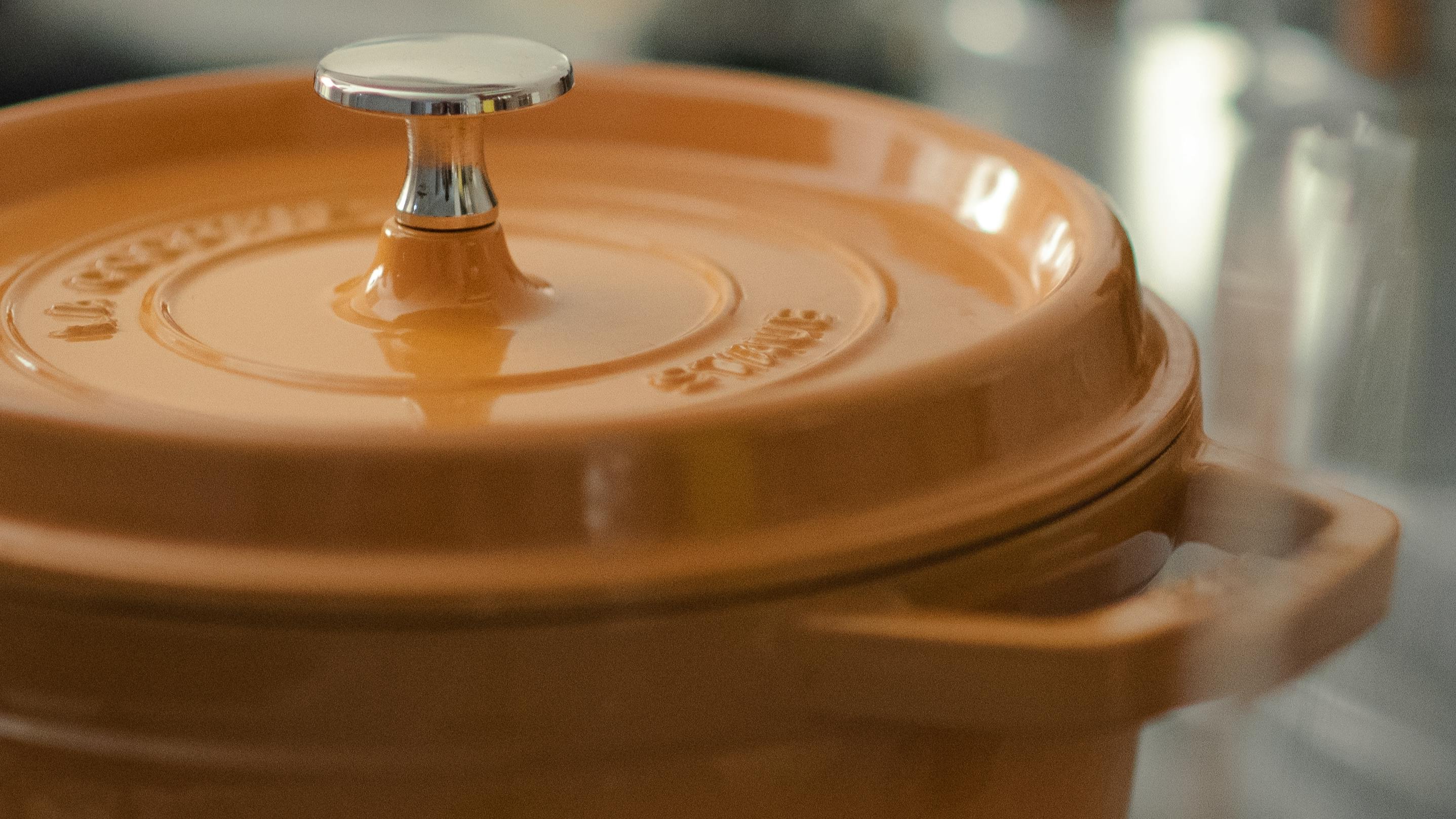 A yellow Staub dutch oven on a stovetop. 