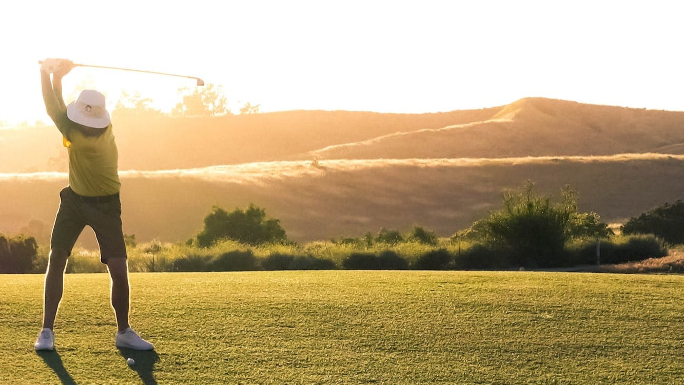 Golfer hitting an iron shot at dawn.