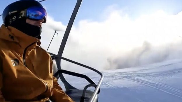 A skier sitting on a chairlift. 