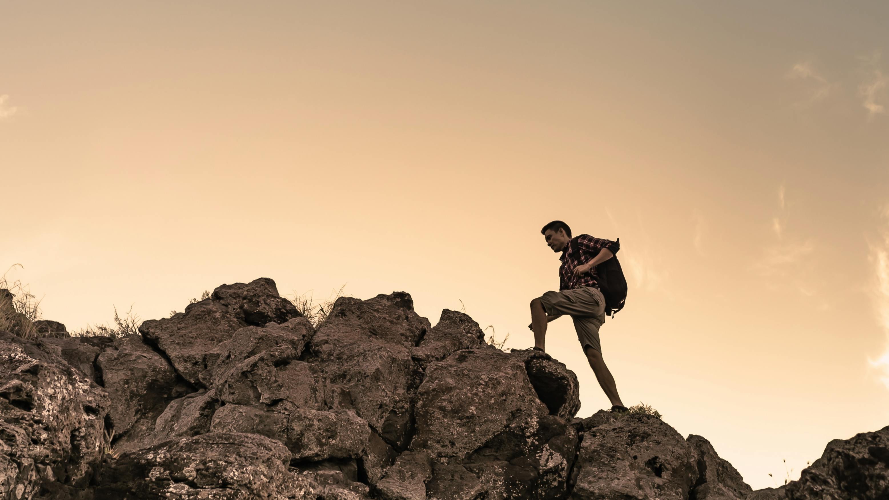 A hiker climbing up a rocky peak. 