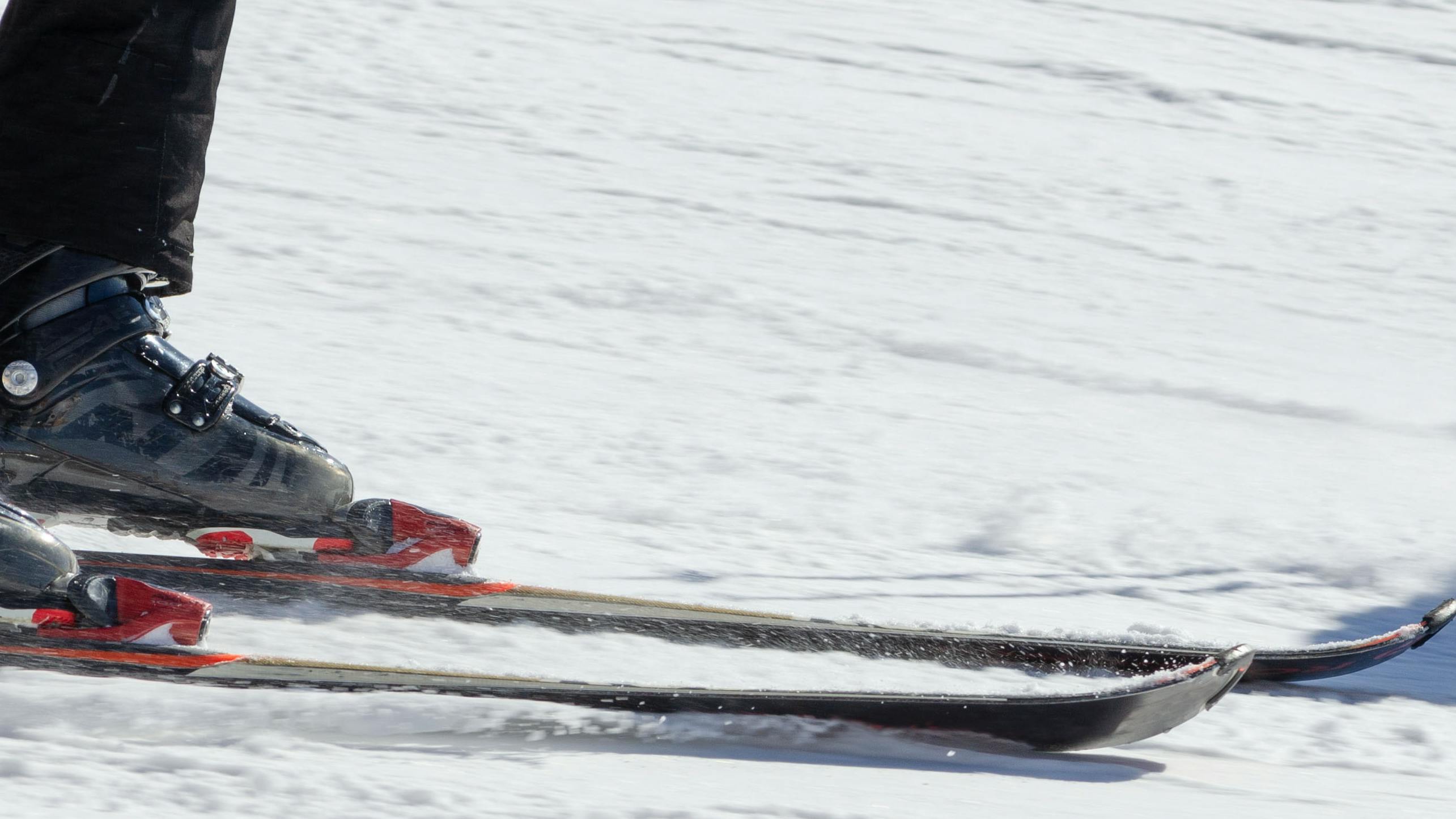 Close up of ski bindings as a skier turns down a ski hill. 