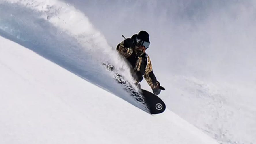 A snowboarder carving down a snowy run on a Ride Snowboard. 