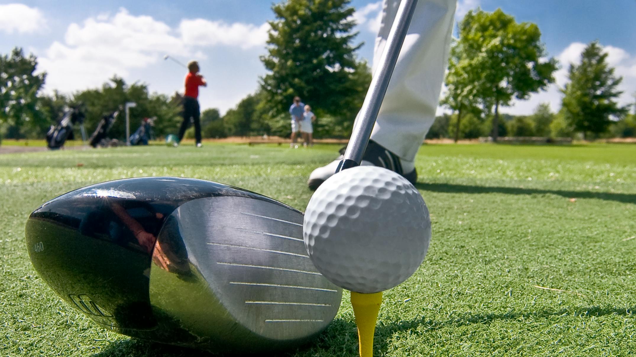 A view from the head of the driver as a golfer prepares to hit a ball off a tee. 