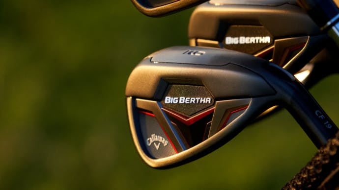 A cluster of Callaway Big Bertha irons in front of an out-of-focus green background. 
