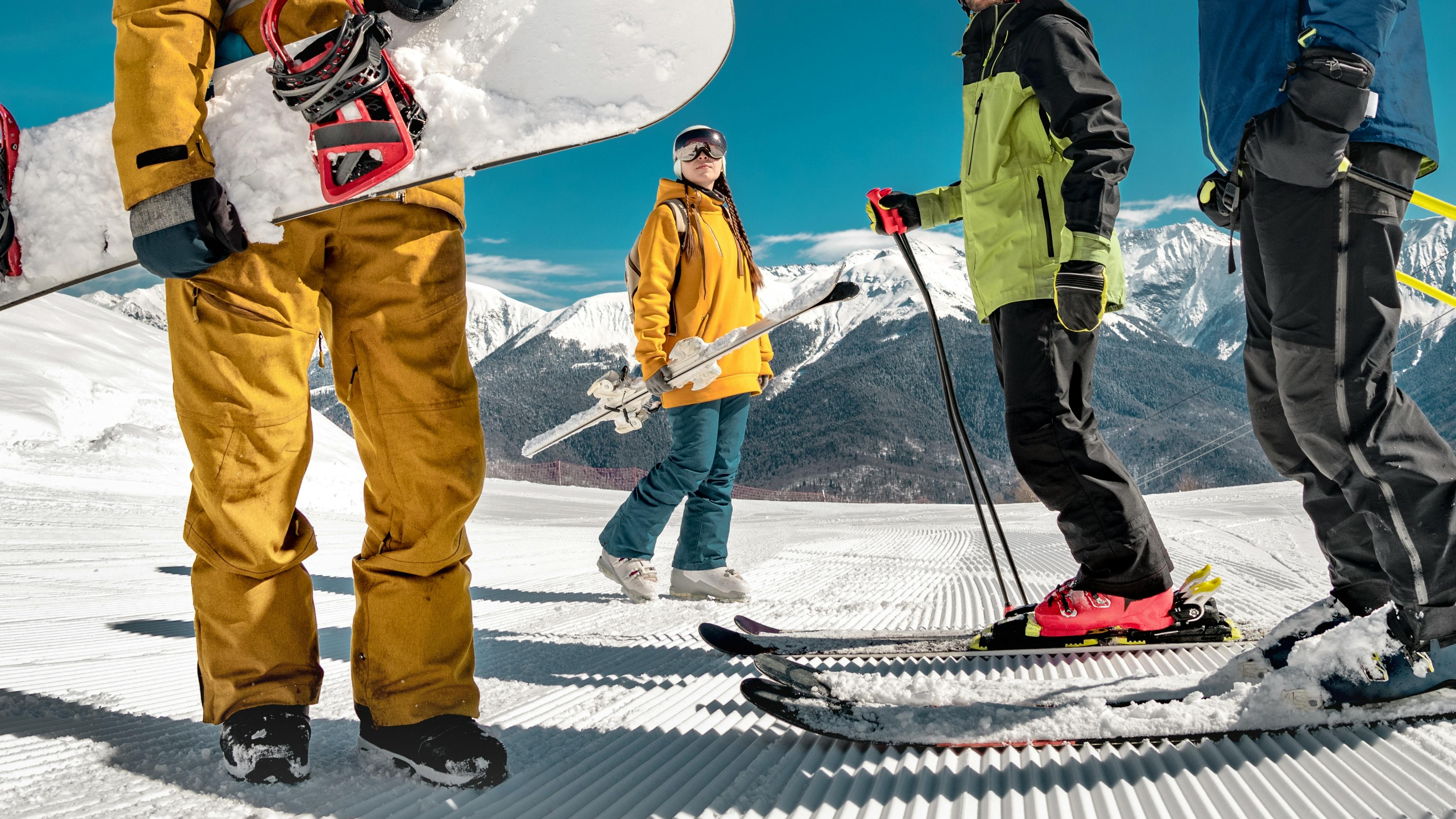 Four skiers in ski  gear standing at the top of a ski run. 