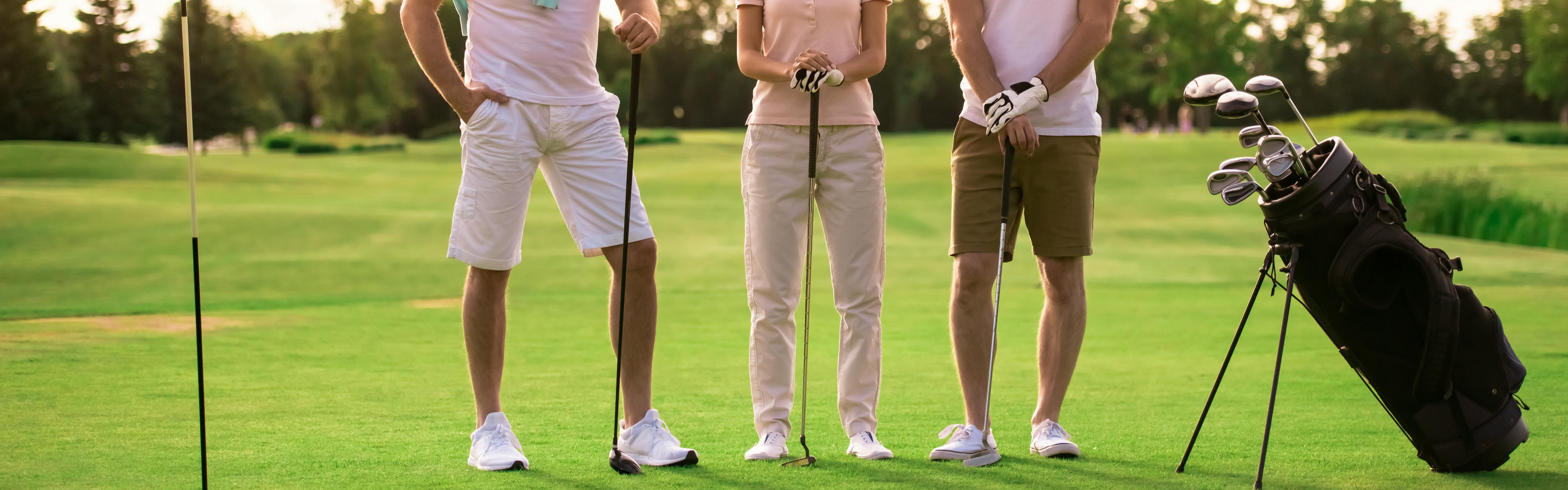 Three golfer stand with their golf clubs. 