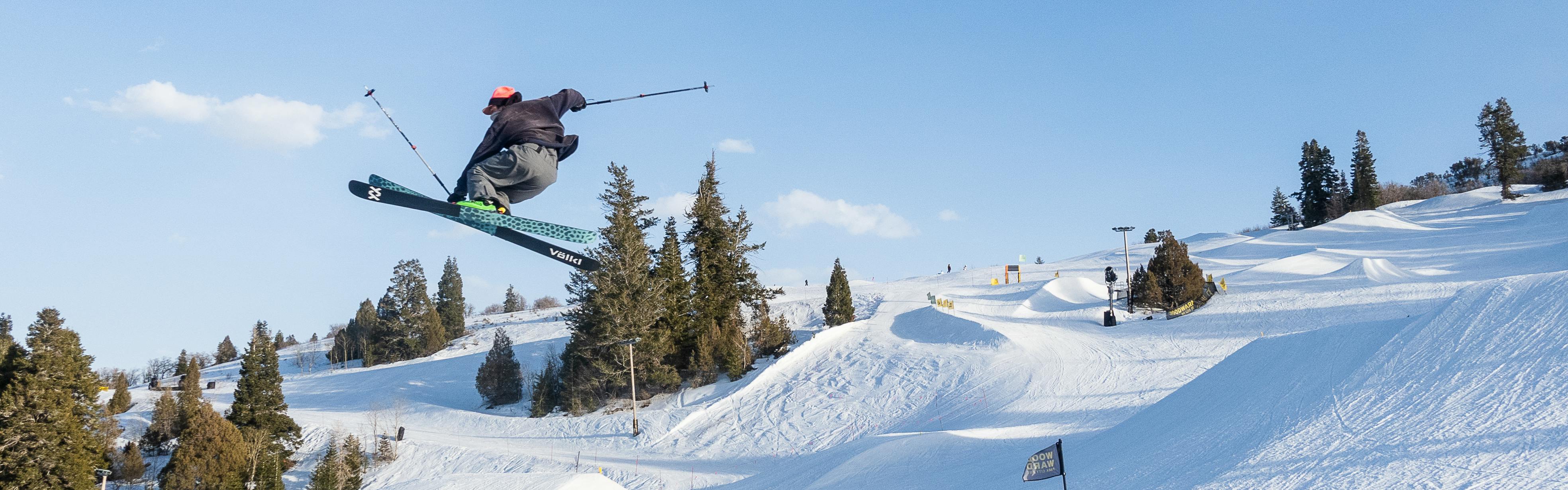 A skier doing a half pipe with the bottom of her skis showing. 