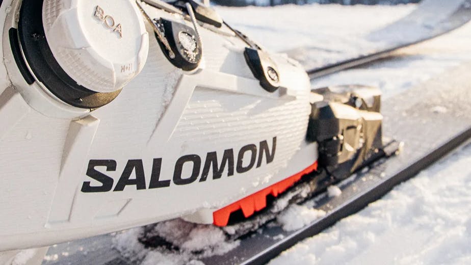 Close up of a white Salomon ski boot clipped into a ski binding. 