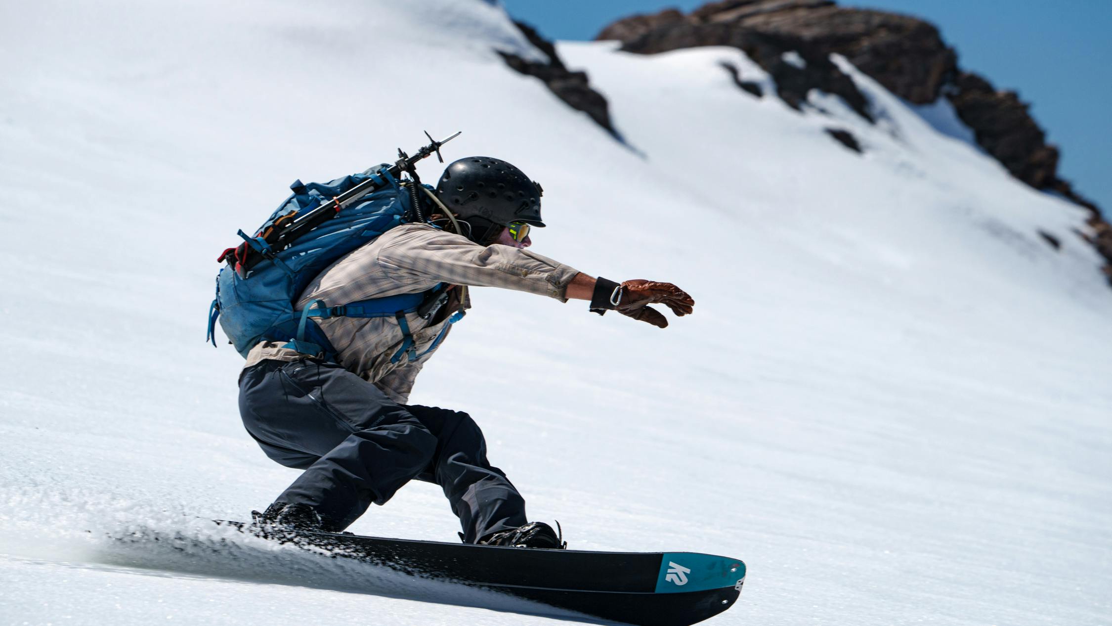 A snowboarder turning down a snowy run. 