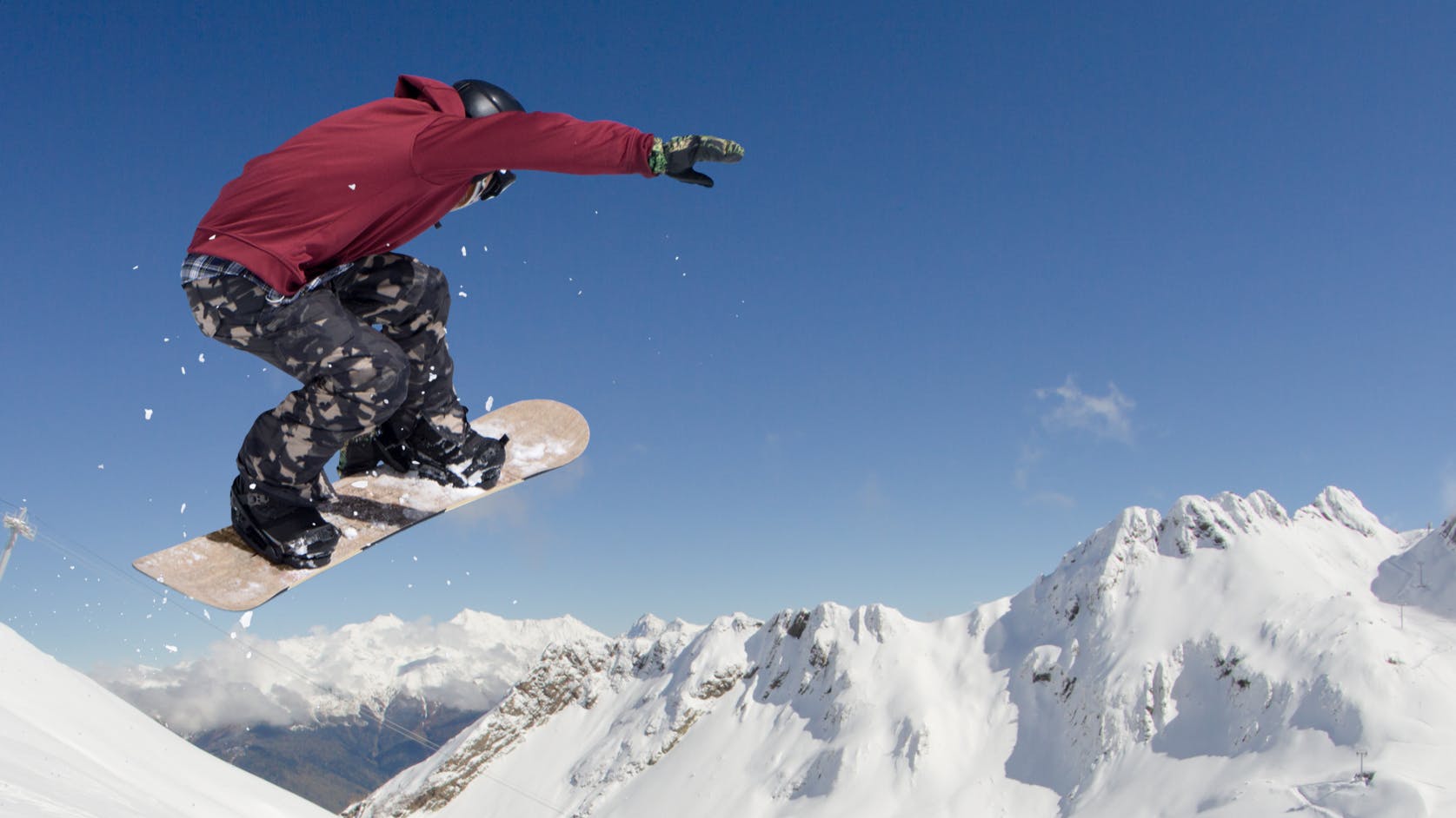 A snowboarder goes off a jump on his snowboard. 