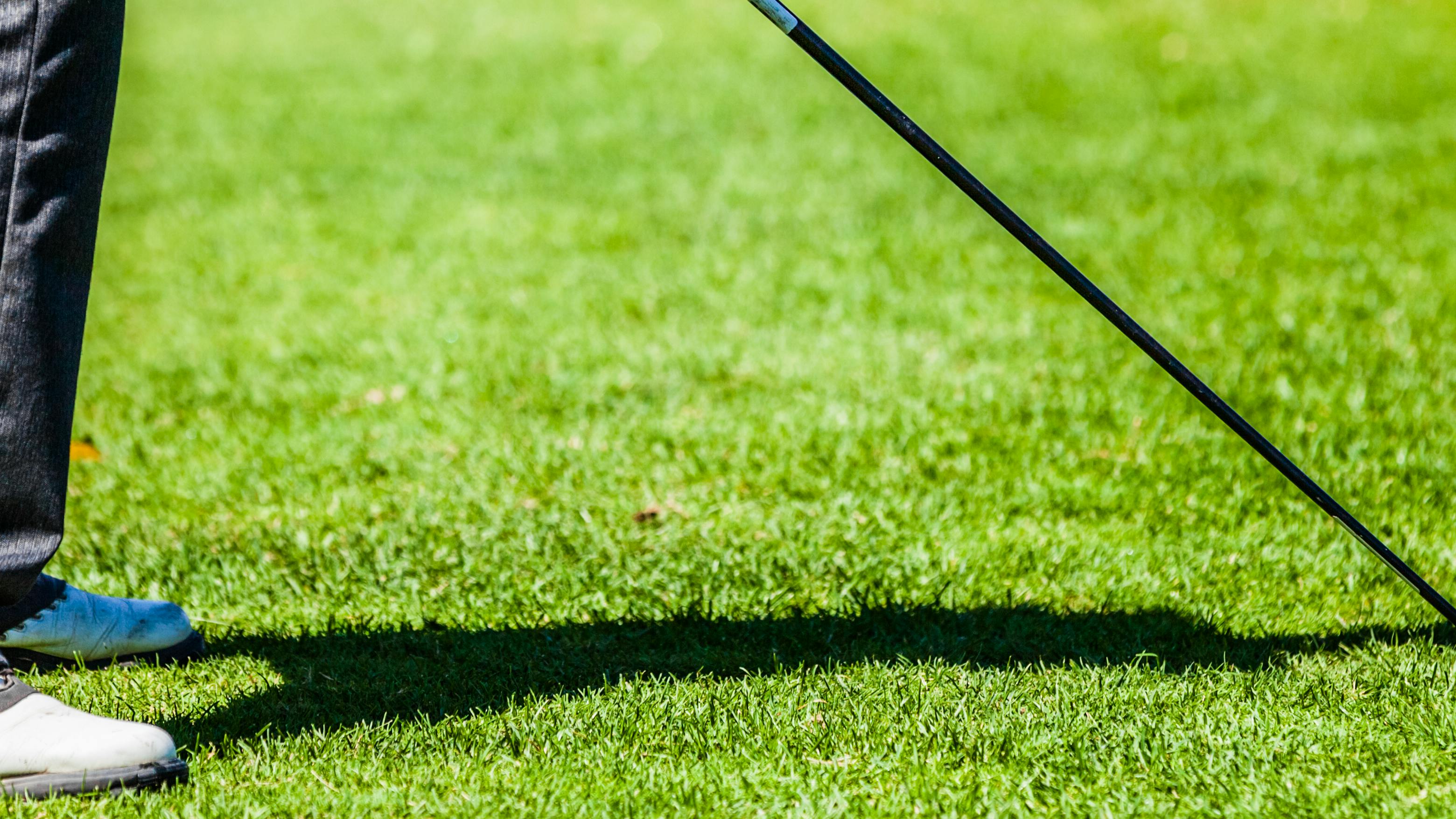 Close up view of a golfer holding a driver to a golf ball.