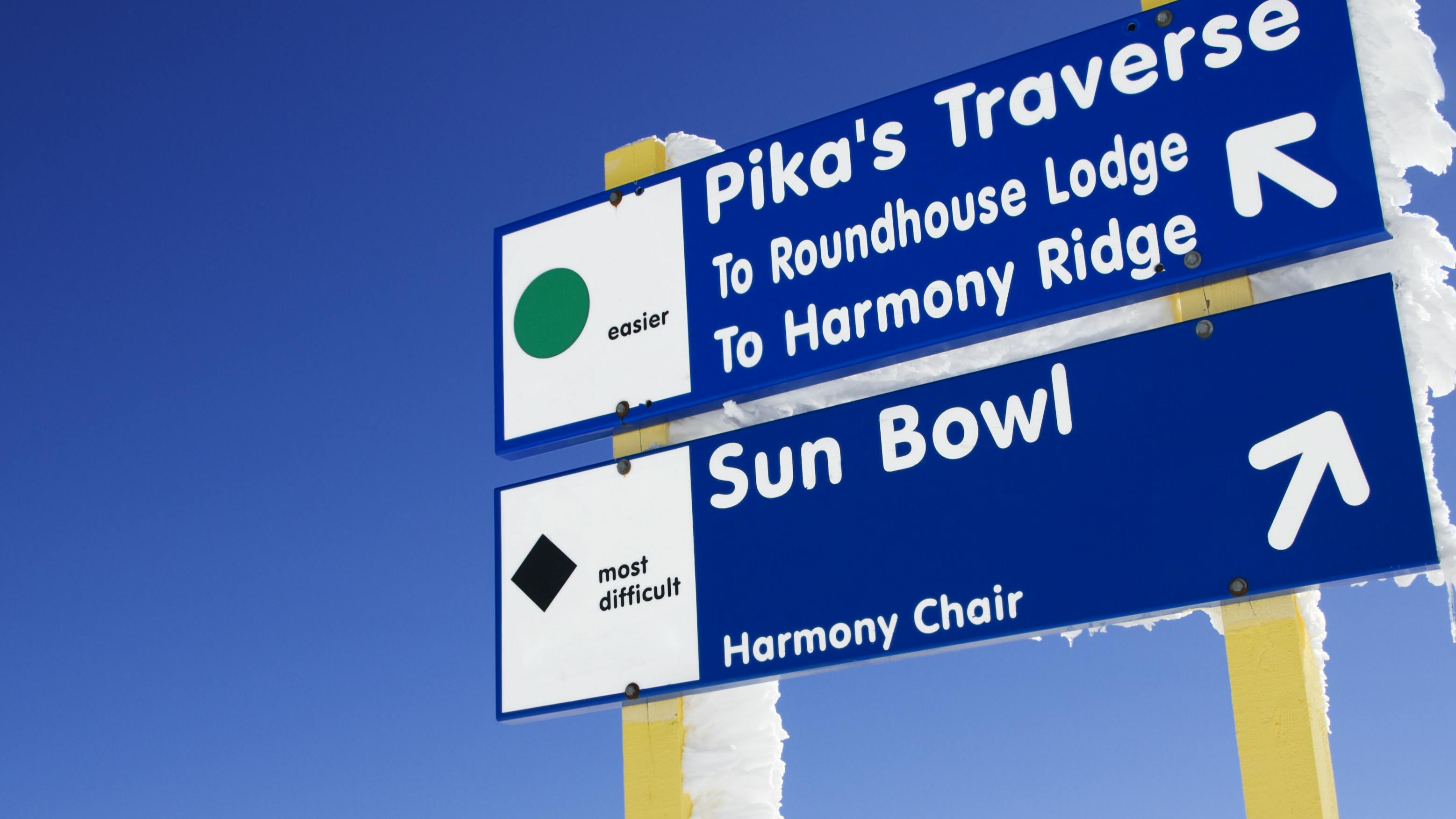 A ski sign with two runs listed, one is a green circle and another is a black diamond. 