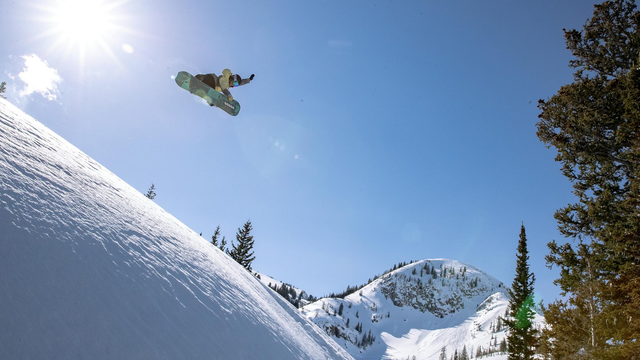 A snowboarder doing a jump off a snowy mountain. 