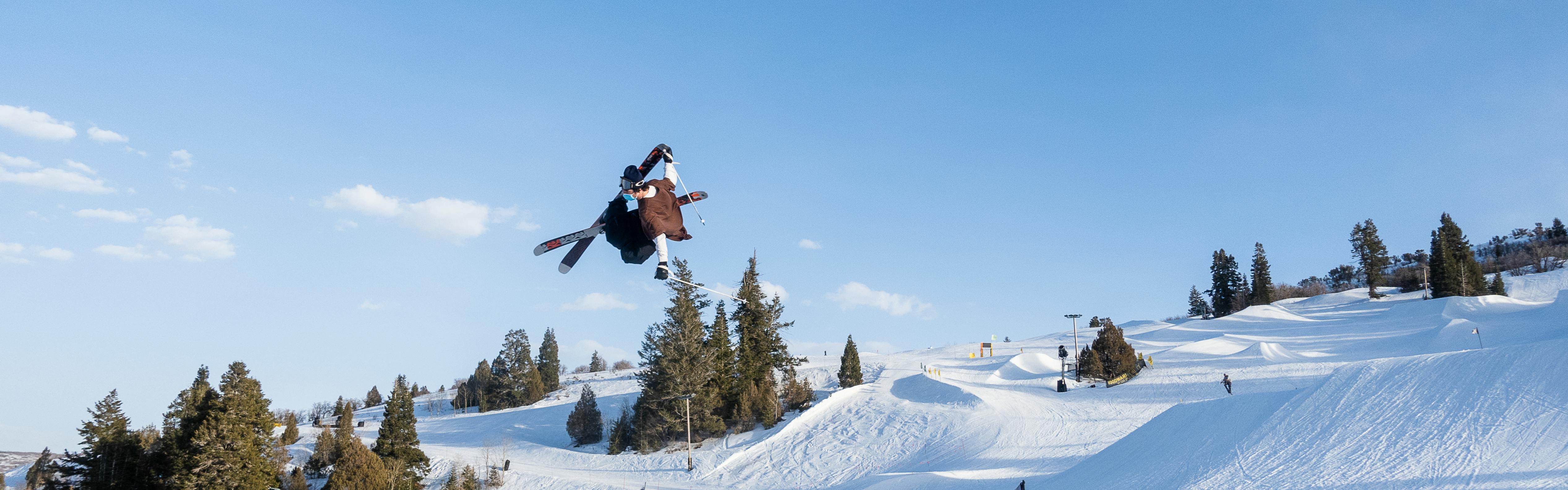 A skier jumping in the air. The bottom of his skis have the K2 symbol on them. 
