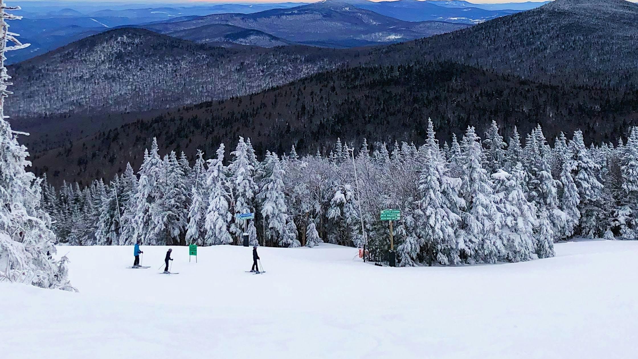 Several skiers standing on the run at a ski resort in Vermont. 