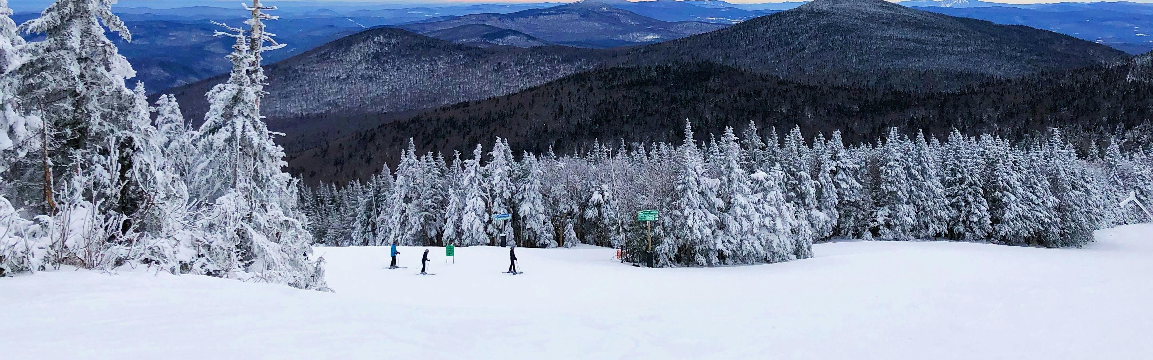 Several skiers standing on the run at a ski resort in Vermont. 