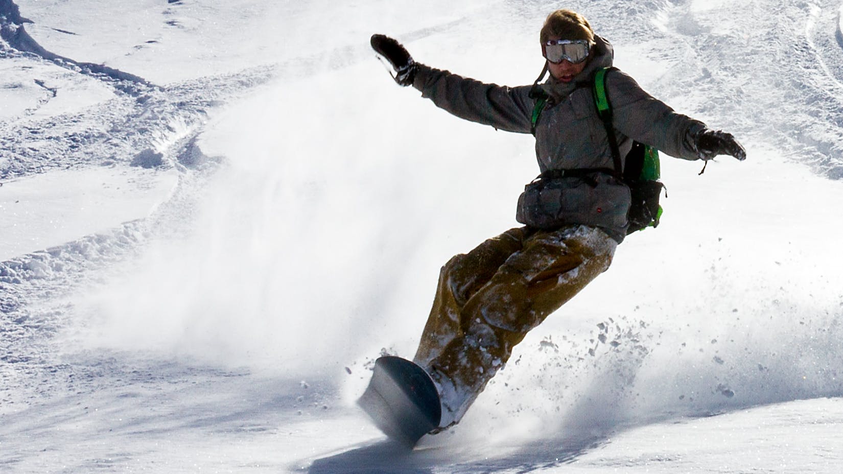 A snowboarder turning in powder. 