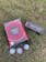 Box on ground with sleeve of golf balls and golf balls prese
