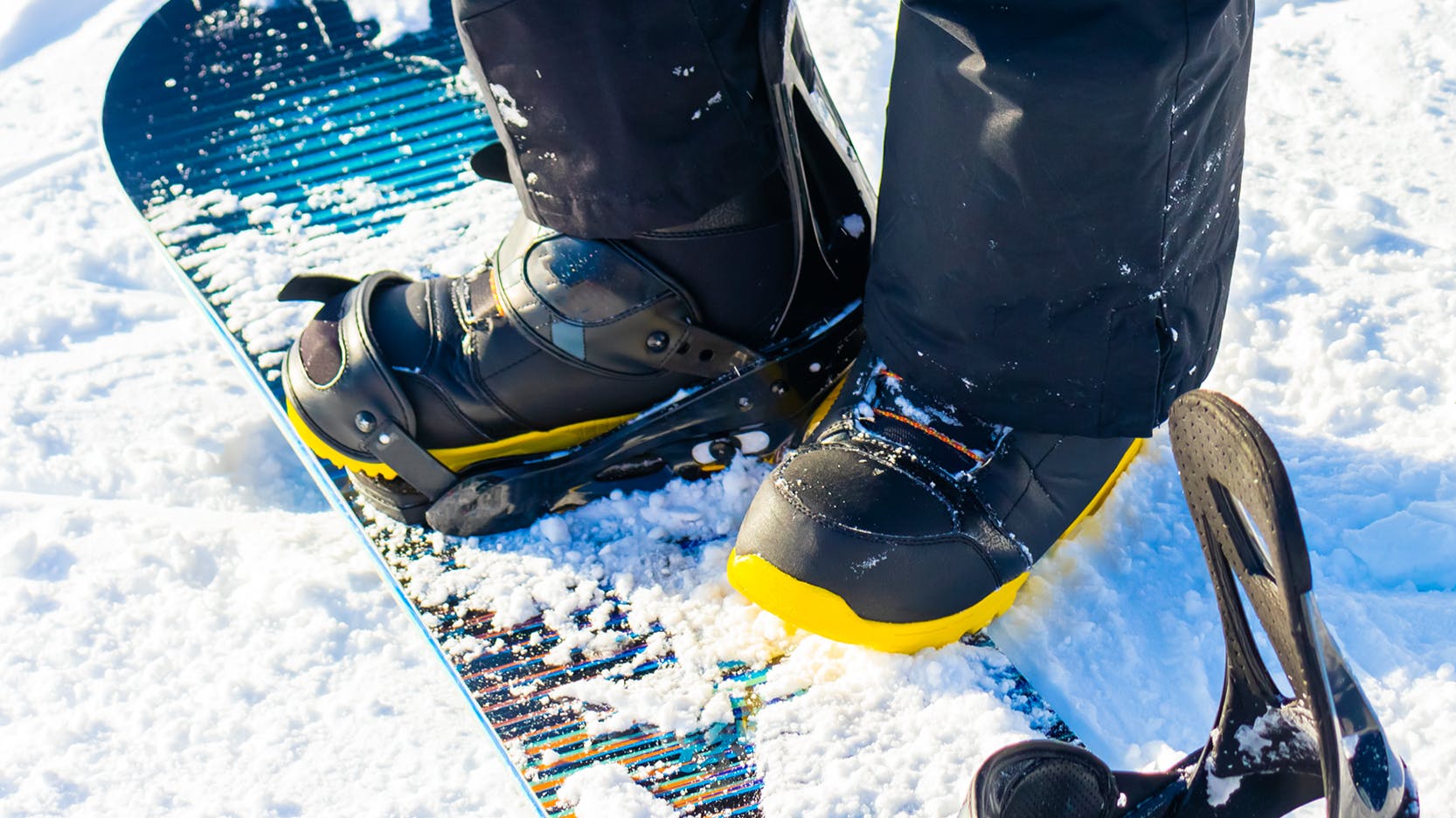 Close up of snowboard boots as a snowboarder stands on his board. 