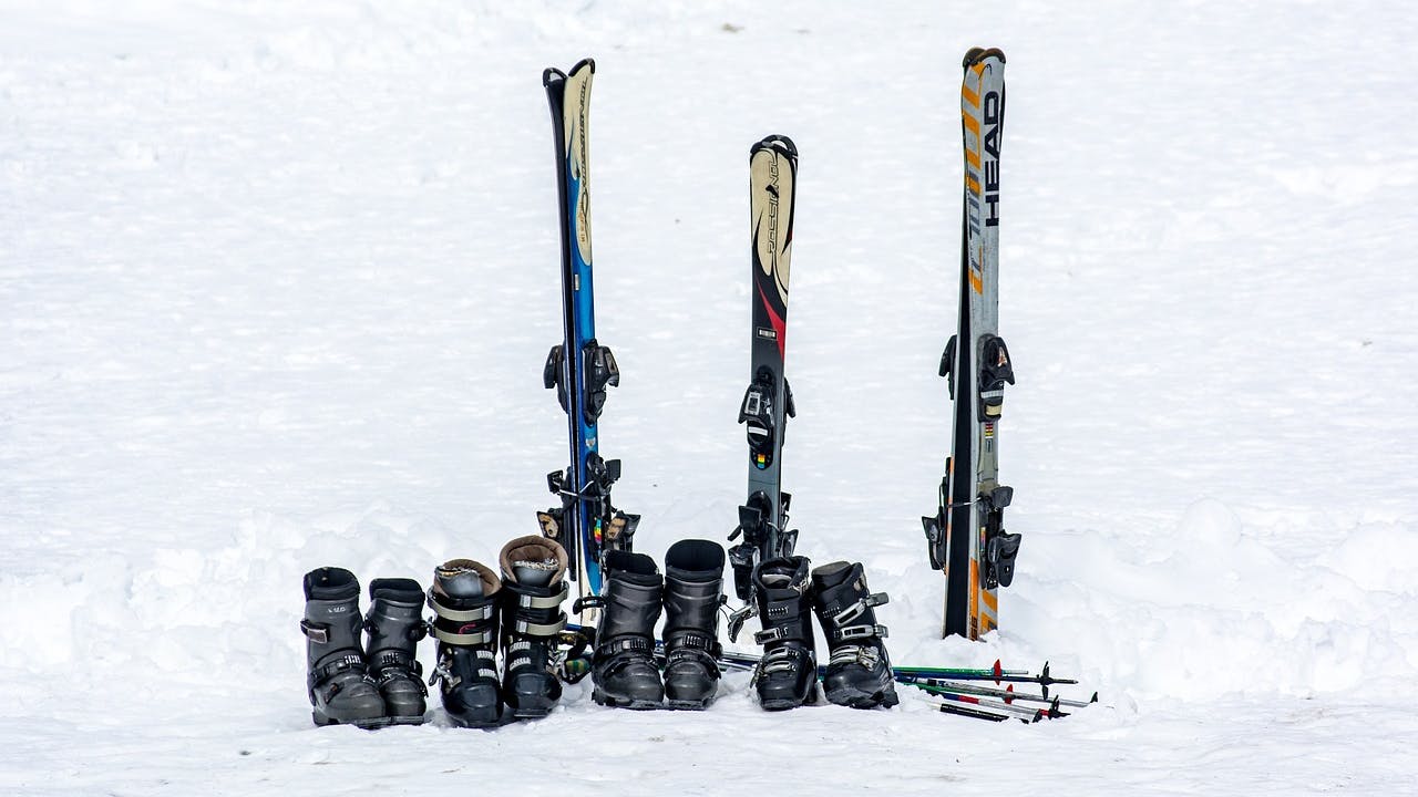 Several ski boots and skis lined up together on snow. 