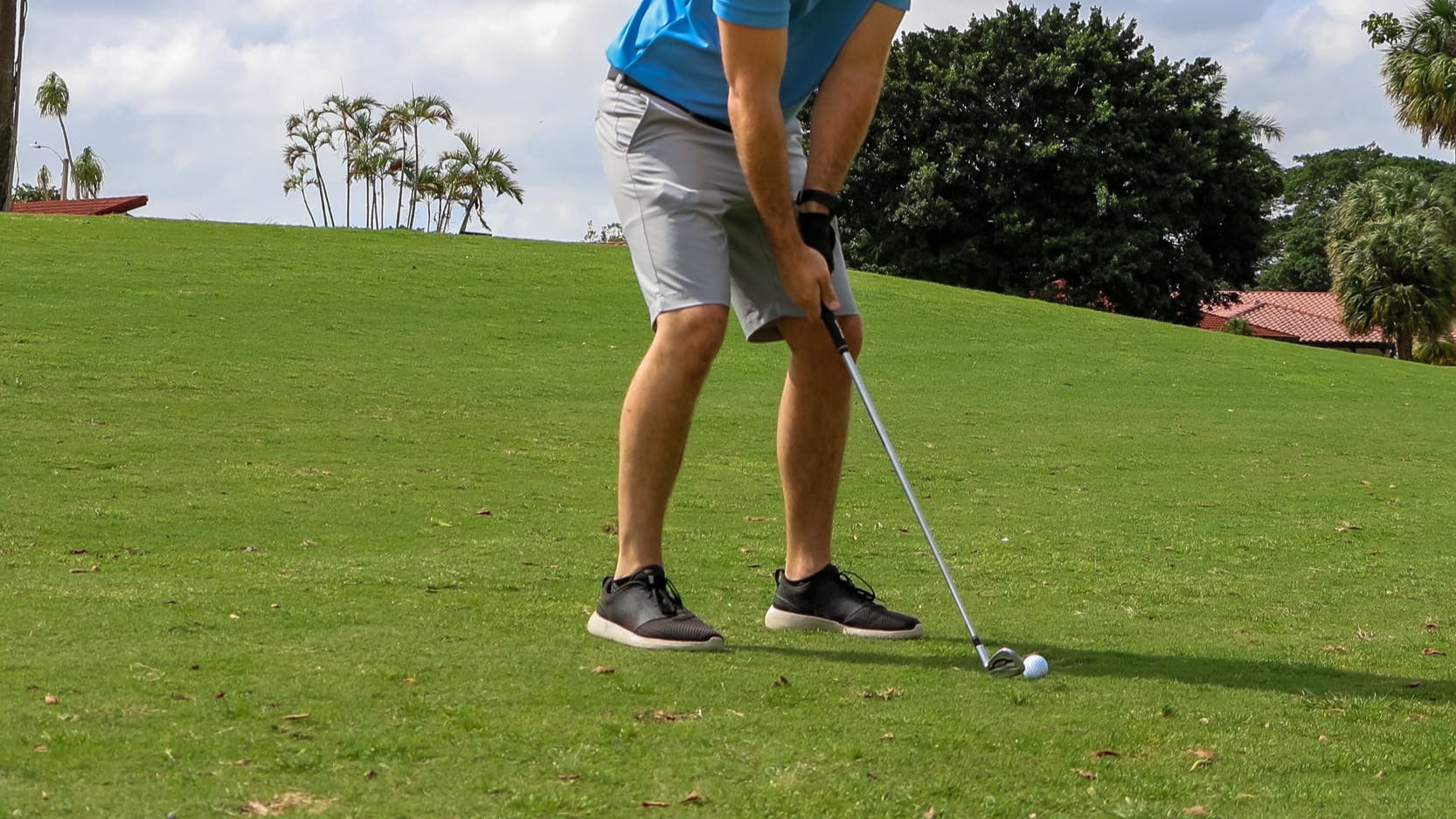 A golfer prepares to hit a golf ball with a wedge. 