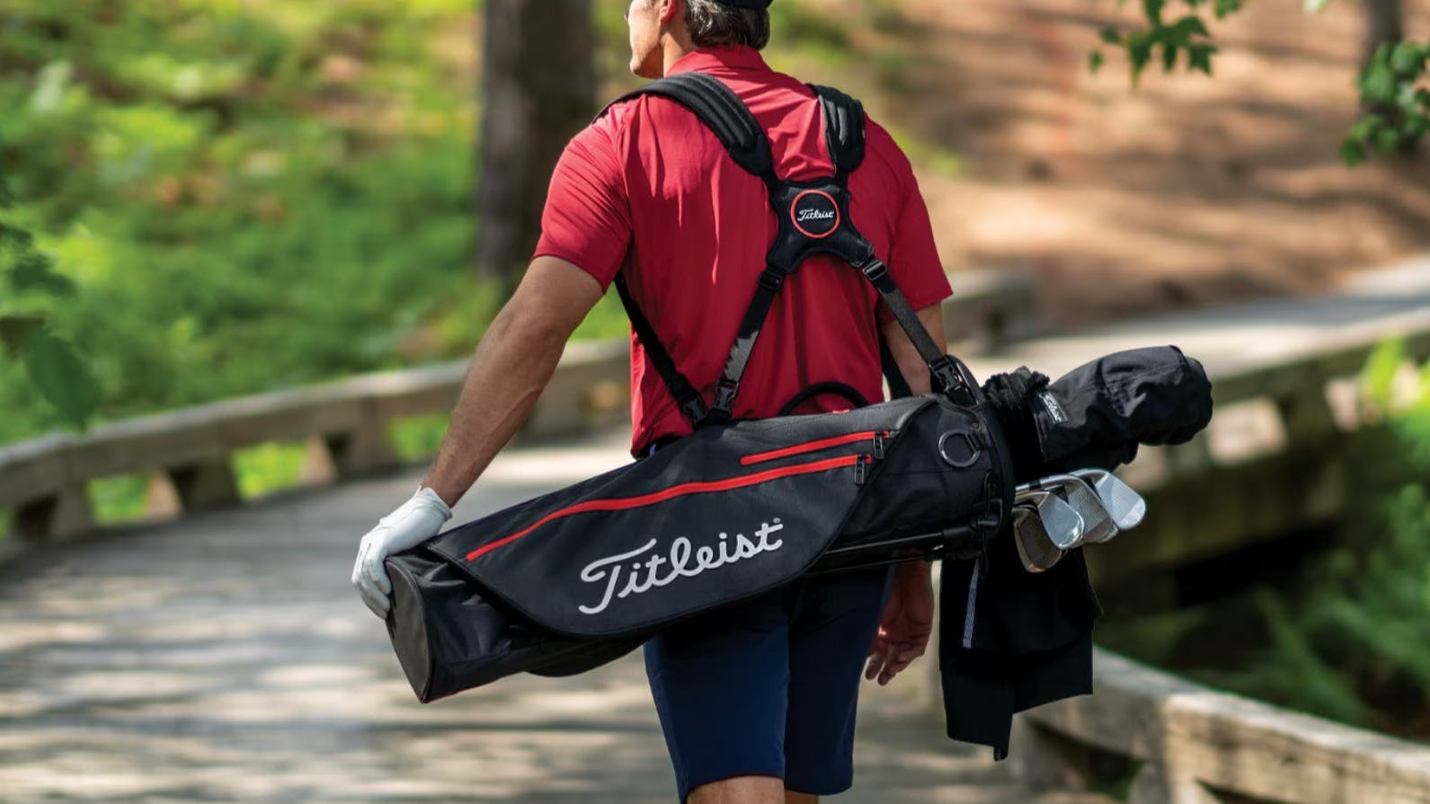 Golfer with Titleist Golf bag walking down a trail. 
