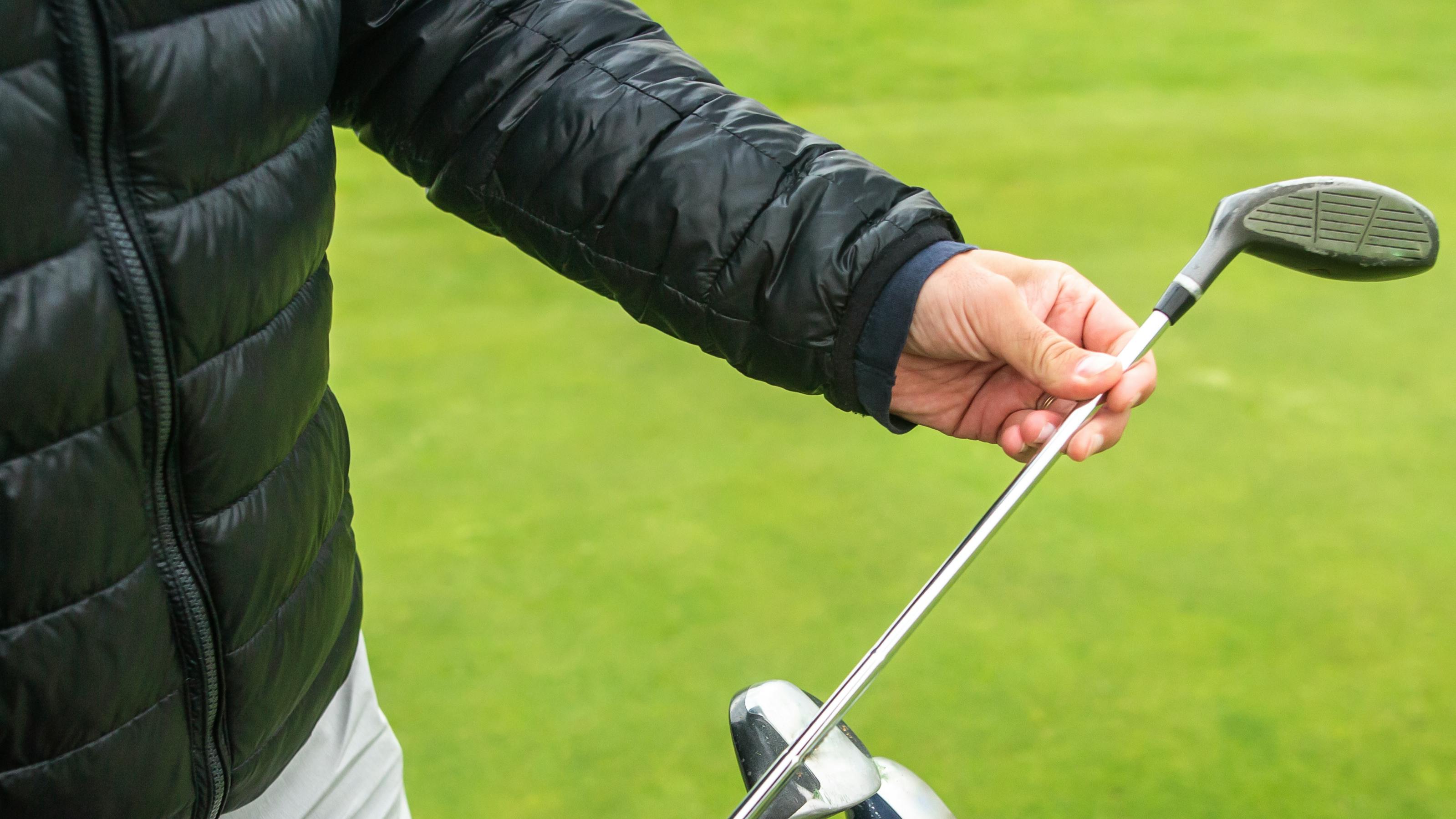 A golfer pulling a club out of a golf bag. 