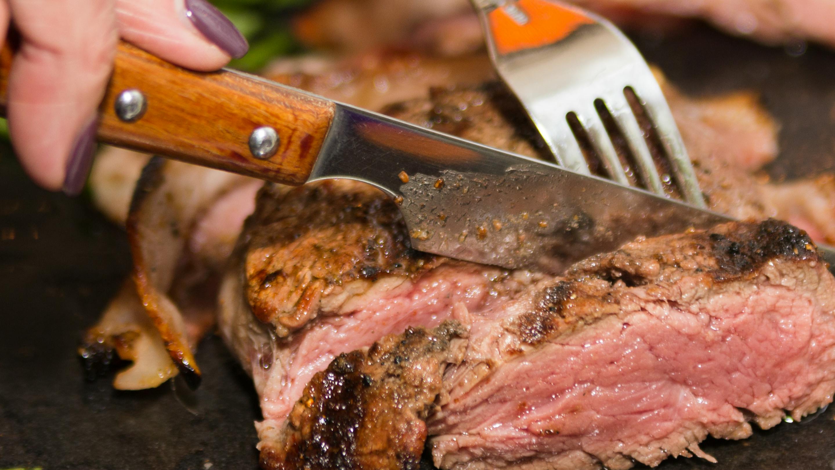 A steak knife slicing through meat.