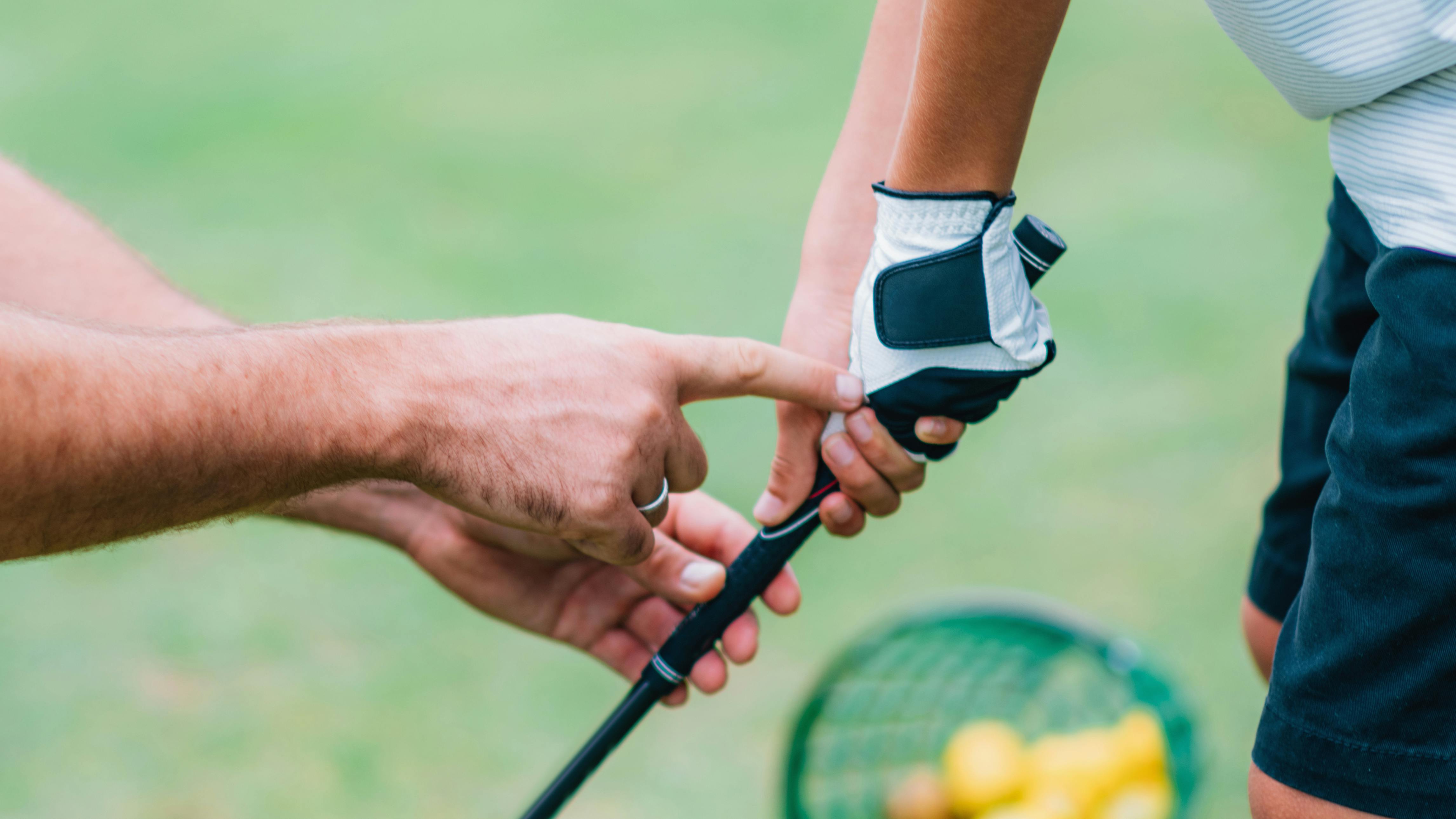 A golf instructor showing someone how to hold a golf grip. 