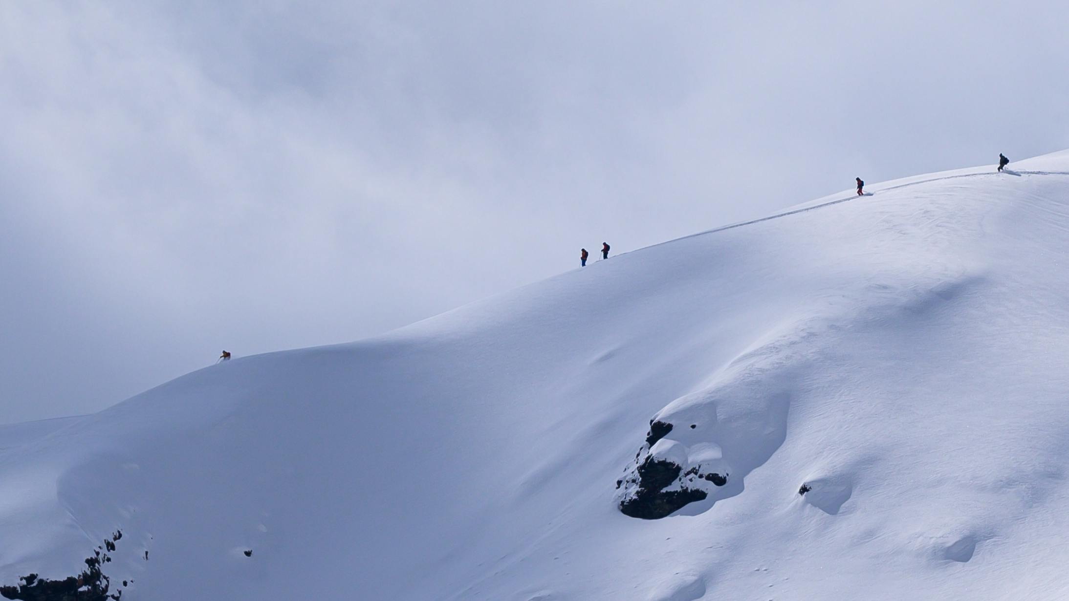 Several skiers standing on top of a ski ridge. 