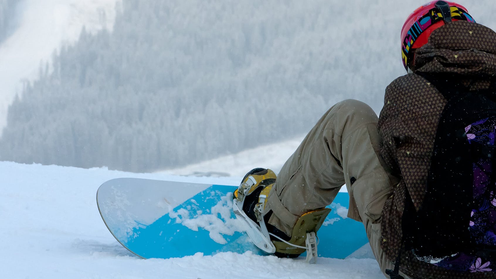 A snowboarder sitting on the snow. 