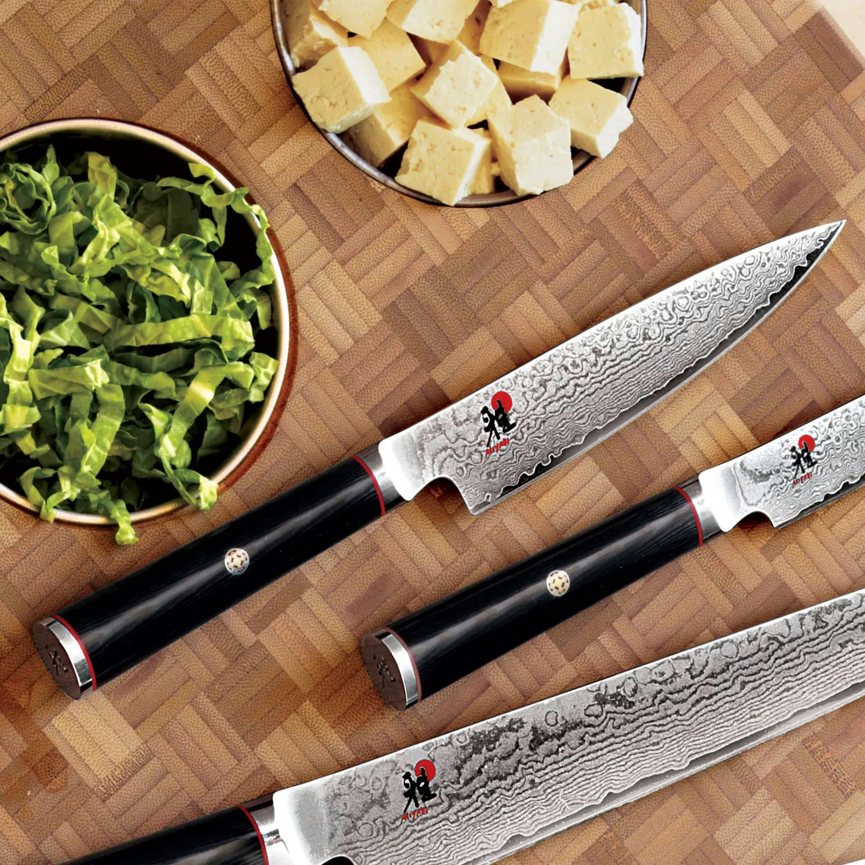 Miyabi Kaizen knives next to some sliced cheese and vegetables. 