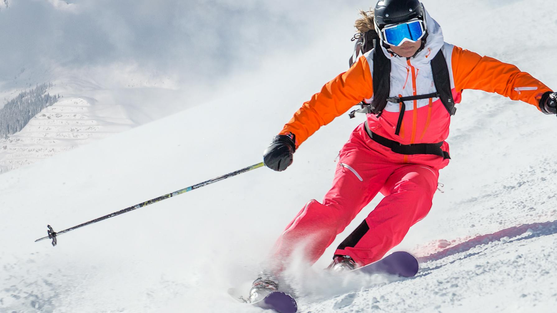 A female skier turning down a hill.