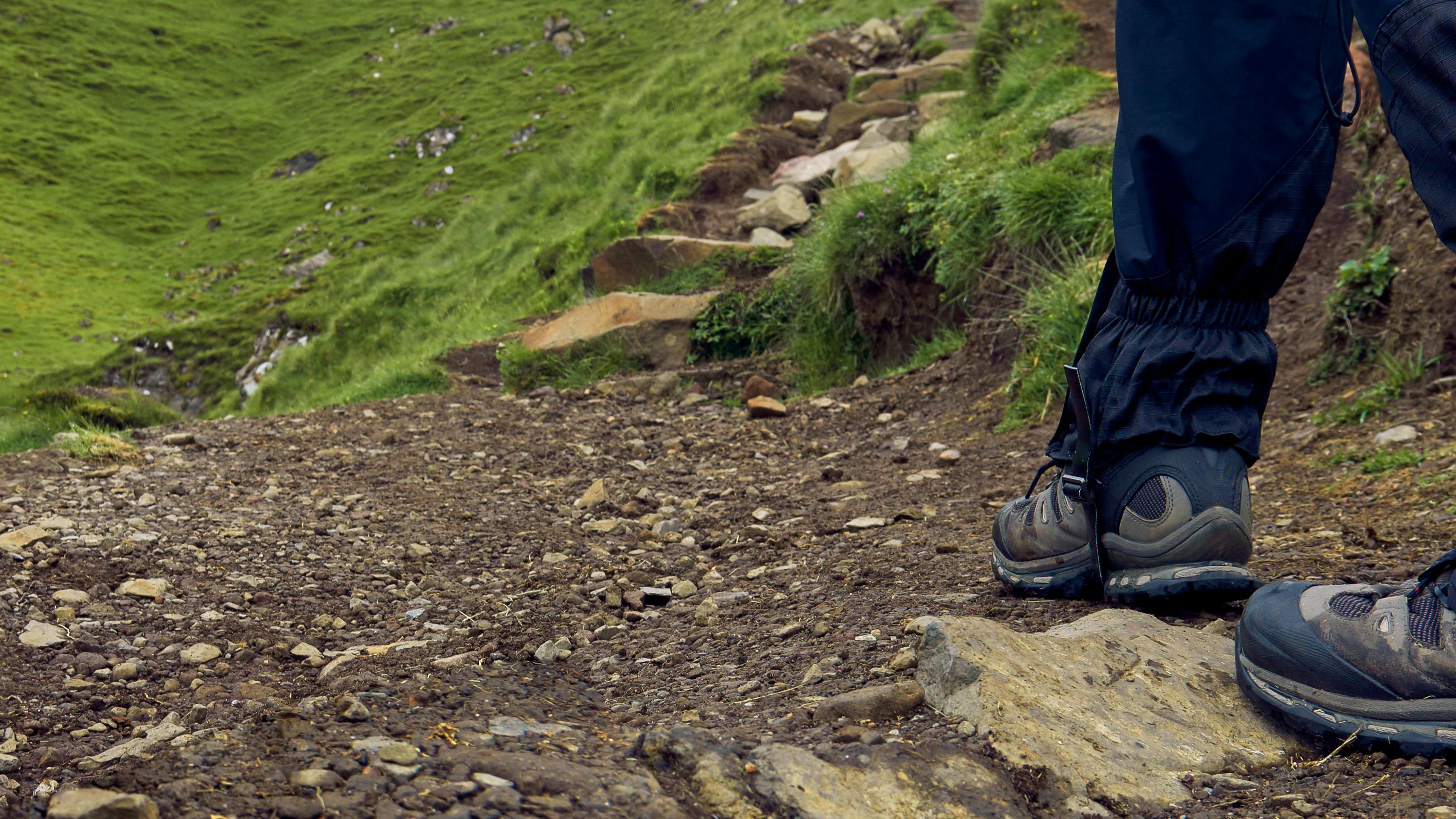 A hiker walking along a trail with hiking gaiters on. 