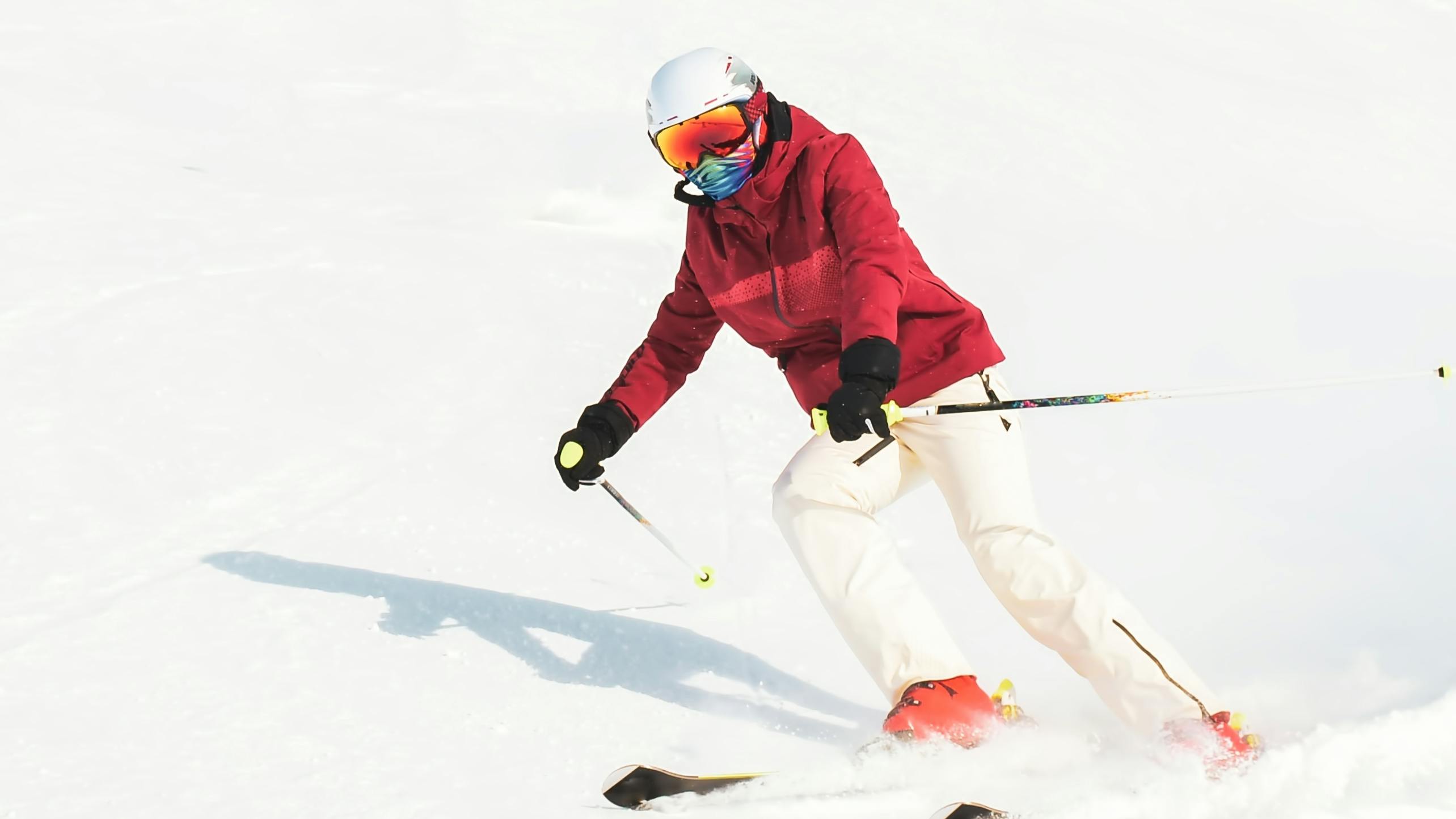 A skier in a red jacket skiing down the slope. 