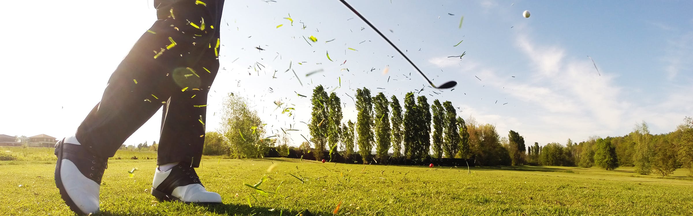 A golfer launching a ball into the air.