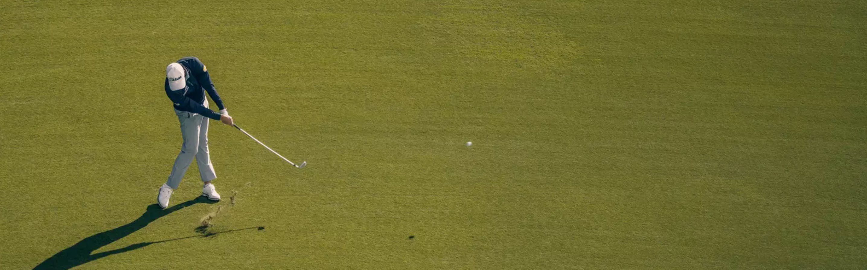 A golfer hitting a golf ball with a club. 