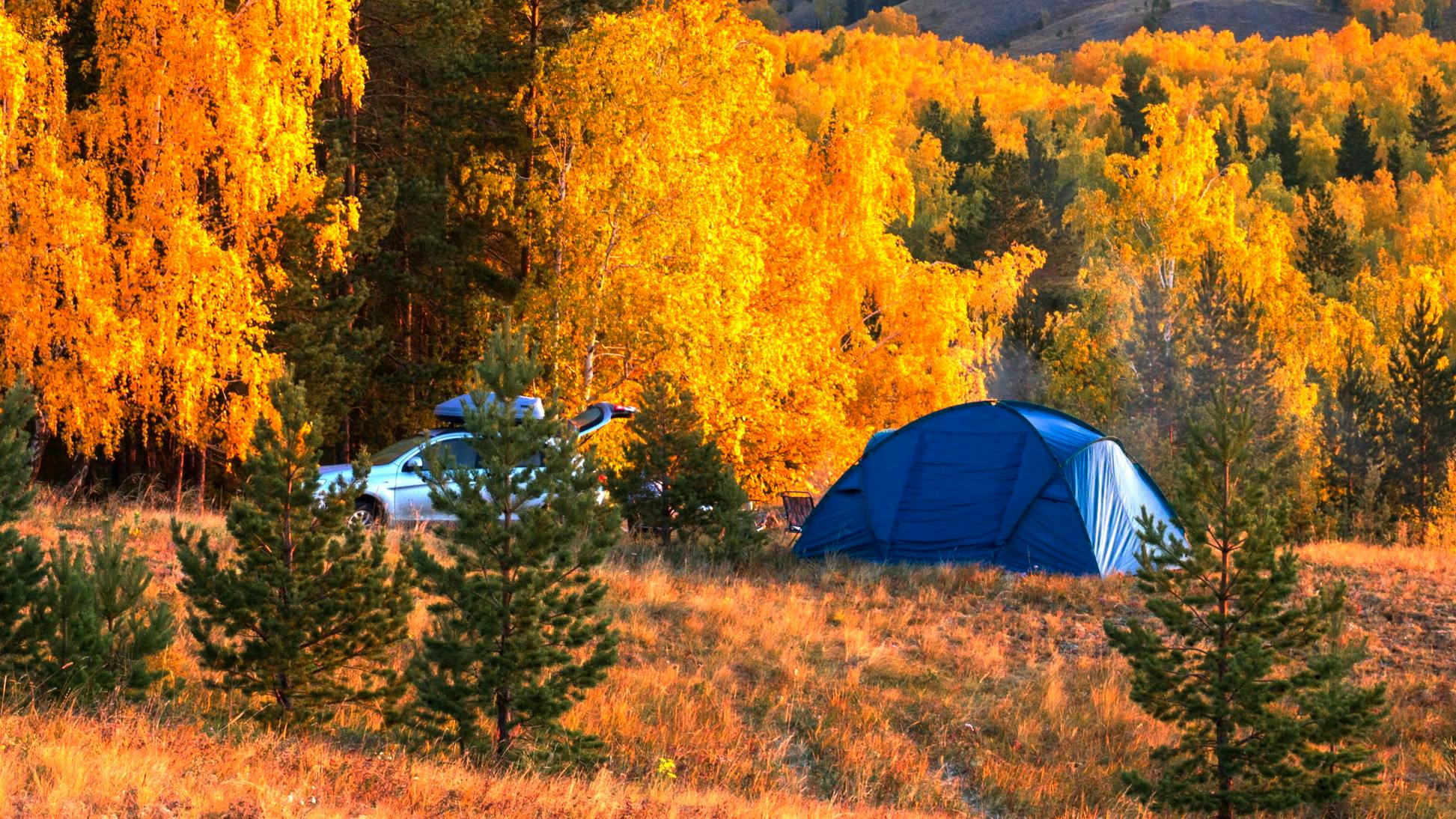 A large tent is pitched in a fall landscape.