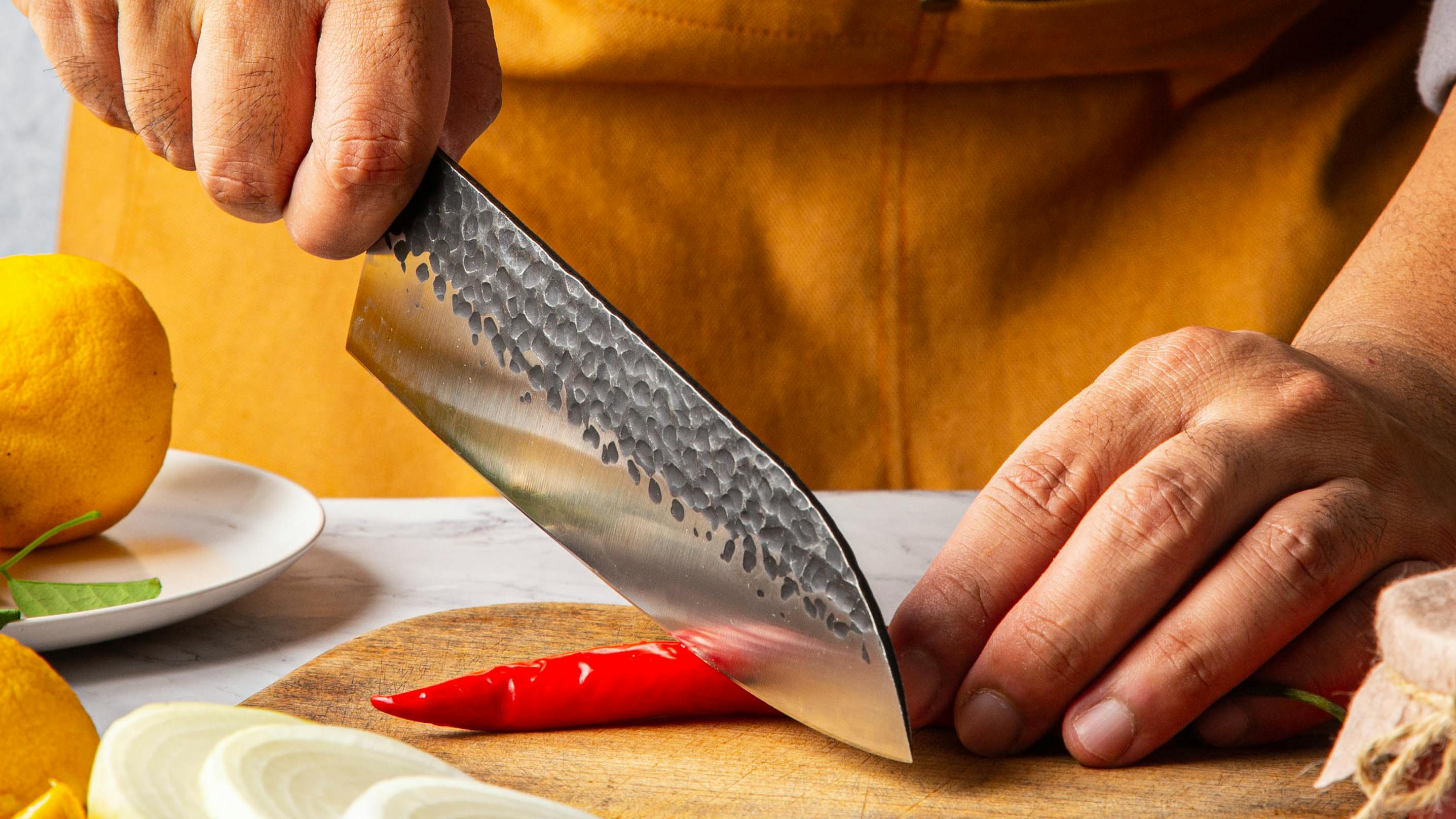 Someone wearing an apron as he sharpens a santou knife. 
