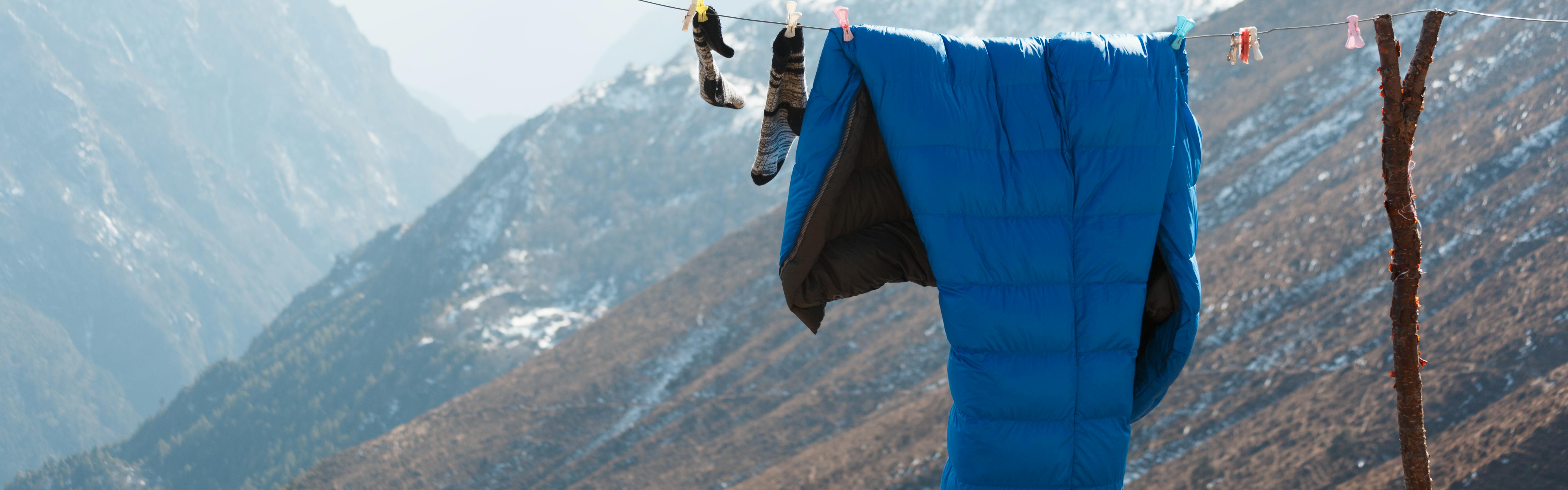 A sleeping bag hanging on a drying like with mountains in the background. 
