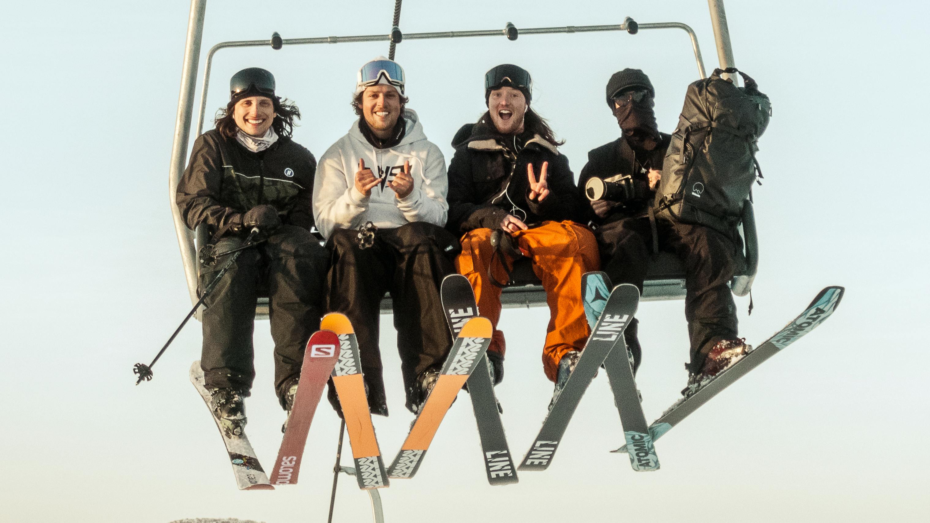 Four skiers on a chairlift all wearing different skis. 