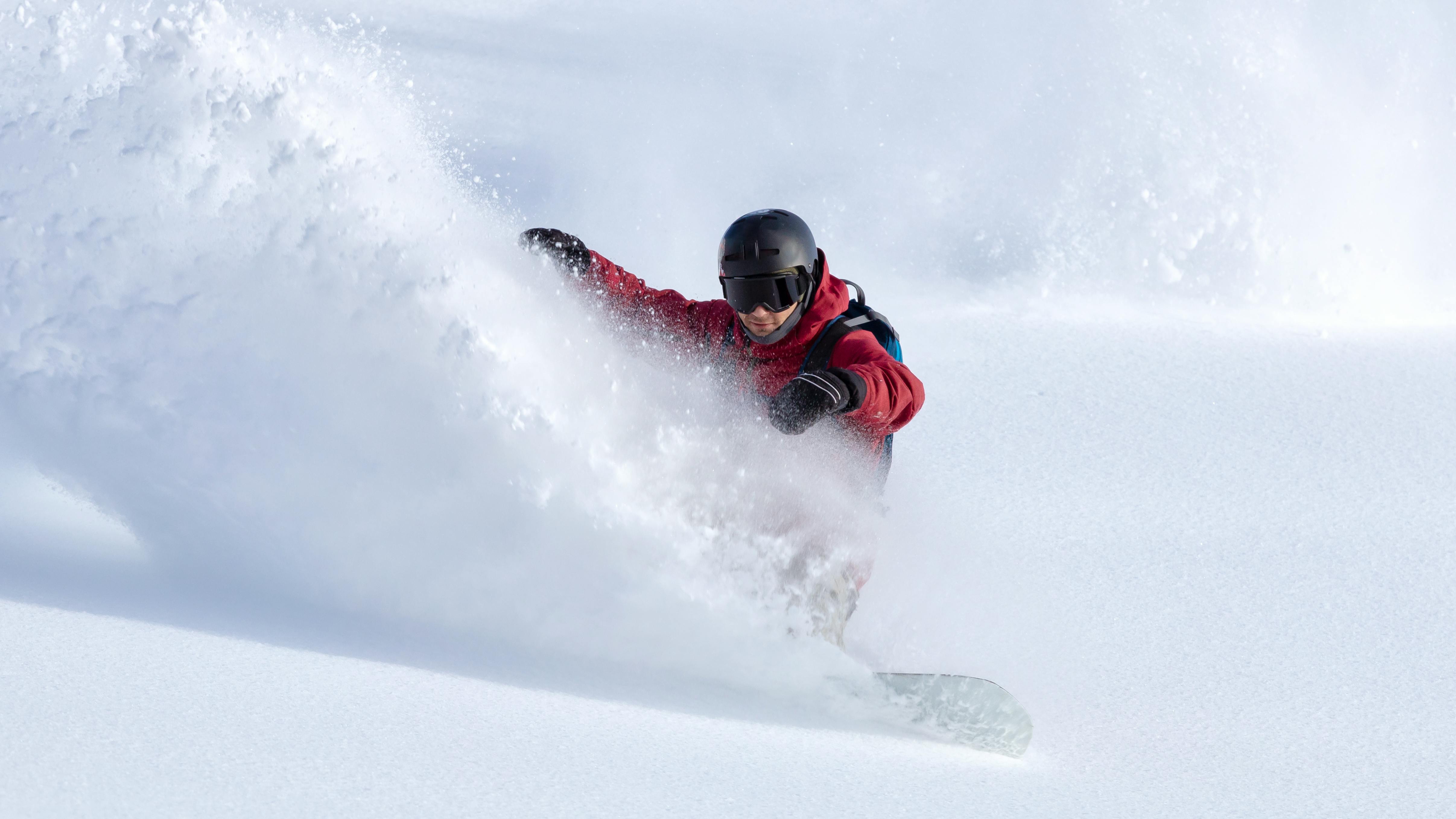 A snowboarder turning in deep powder. 