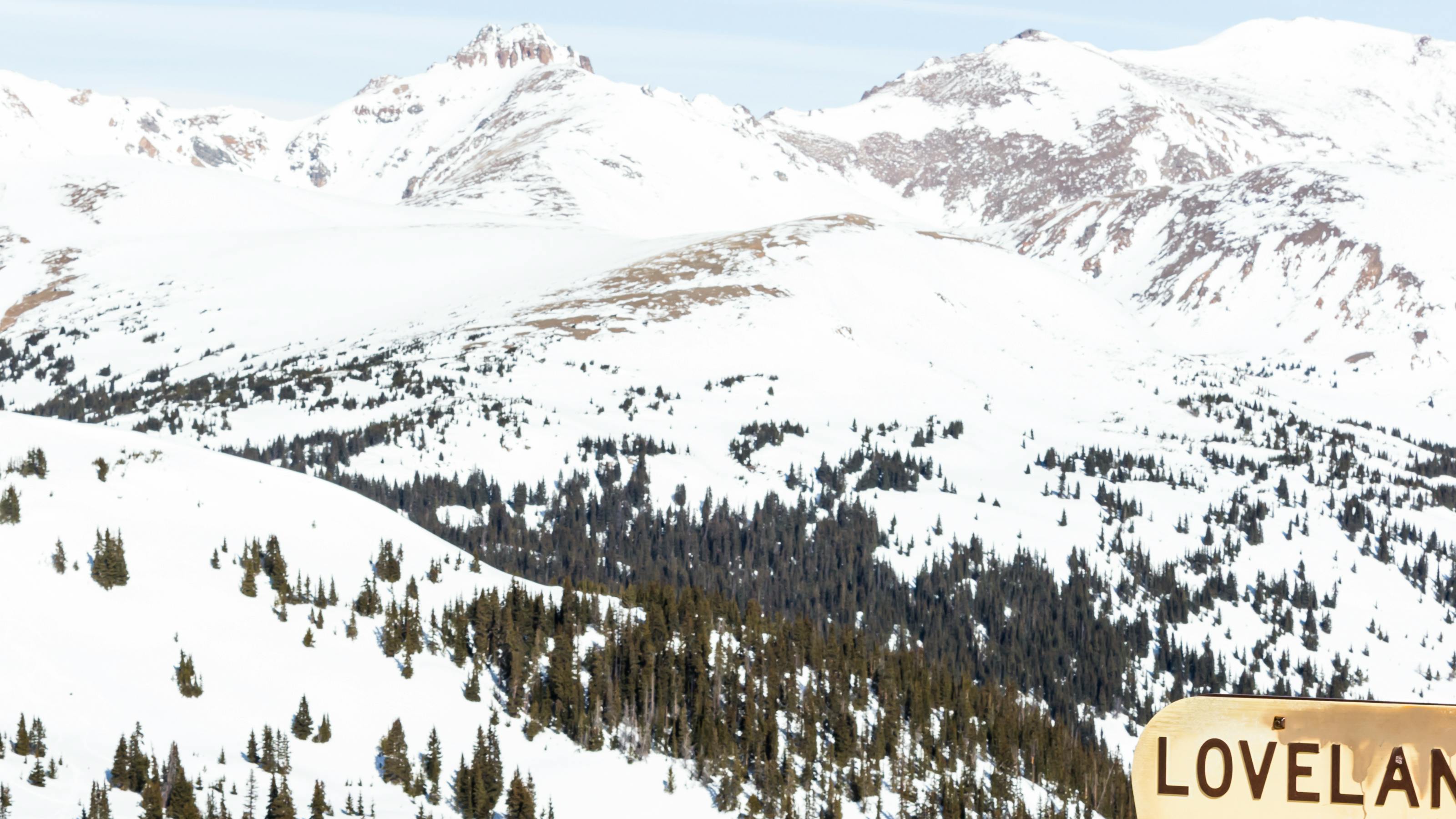 A snowy mountain range with a sign that says "Loveland Pass" in the bottom corner. 