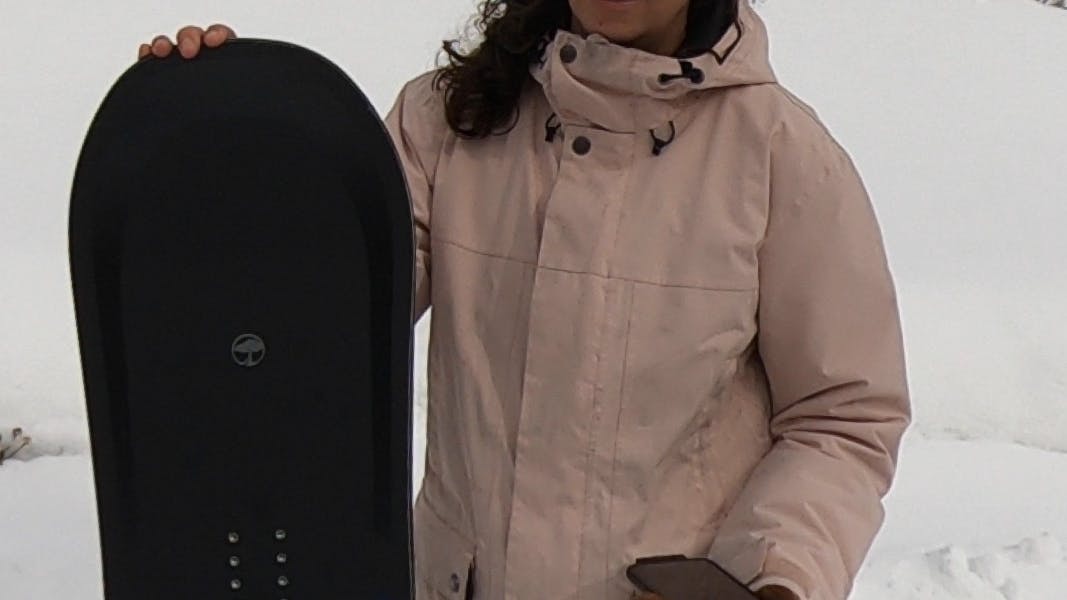 A woman holding the Arbor Formula Rocker Snowboard.