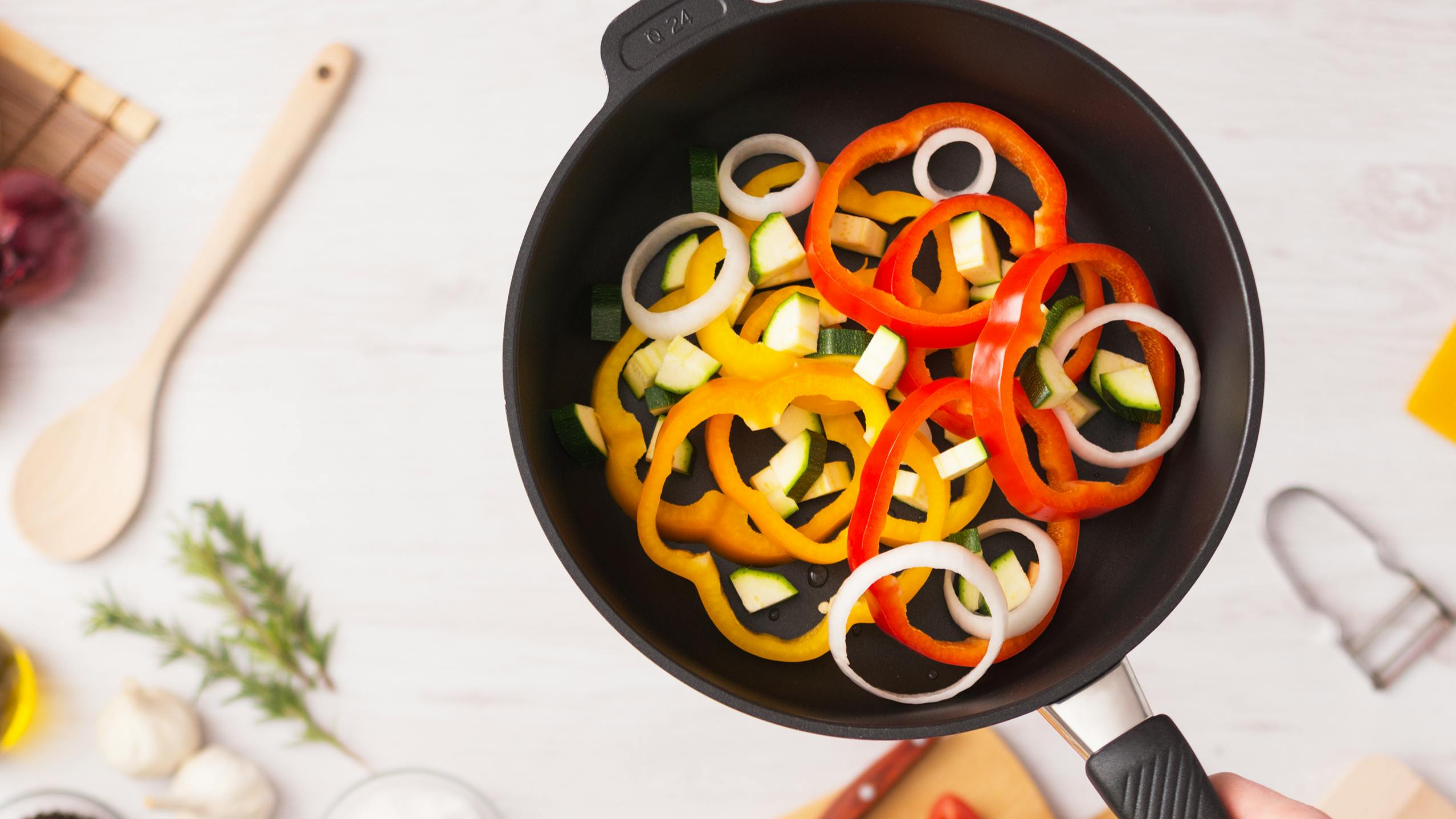 Top down view of a nonstick pan with peppers and zuchinni in it. 